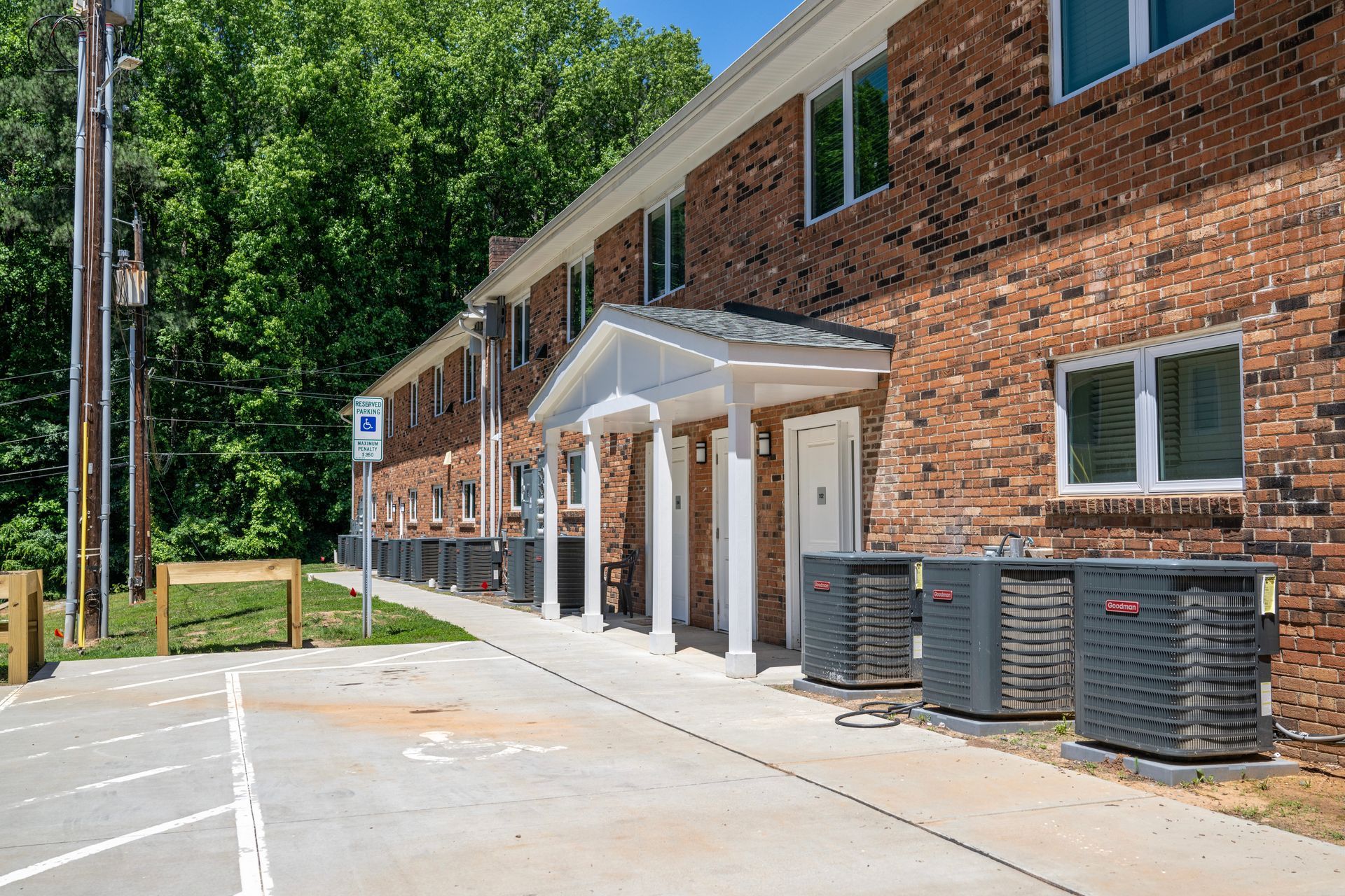 A brick apartment building with a parking lot in front of it.