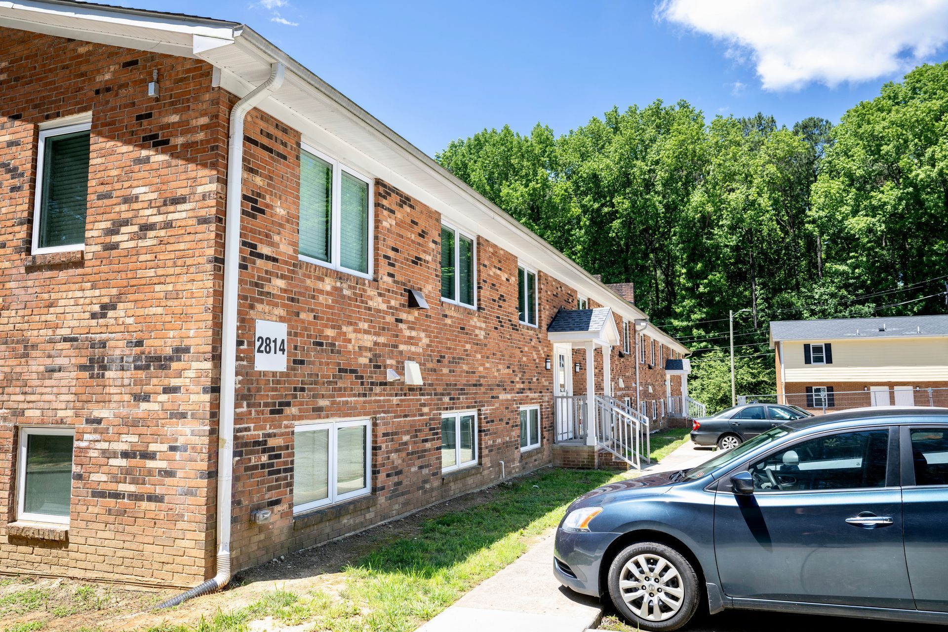 A car is parked in front of a brick apartment building.