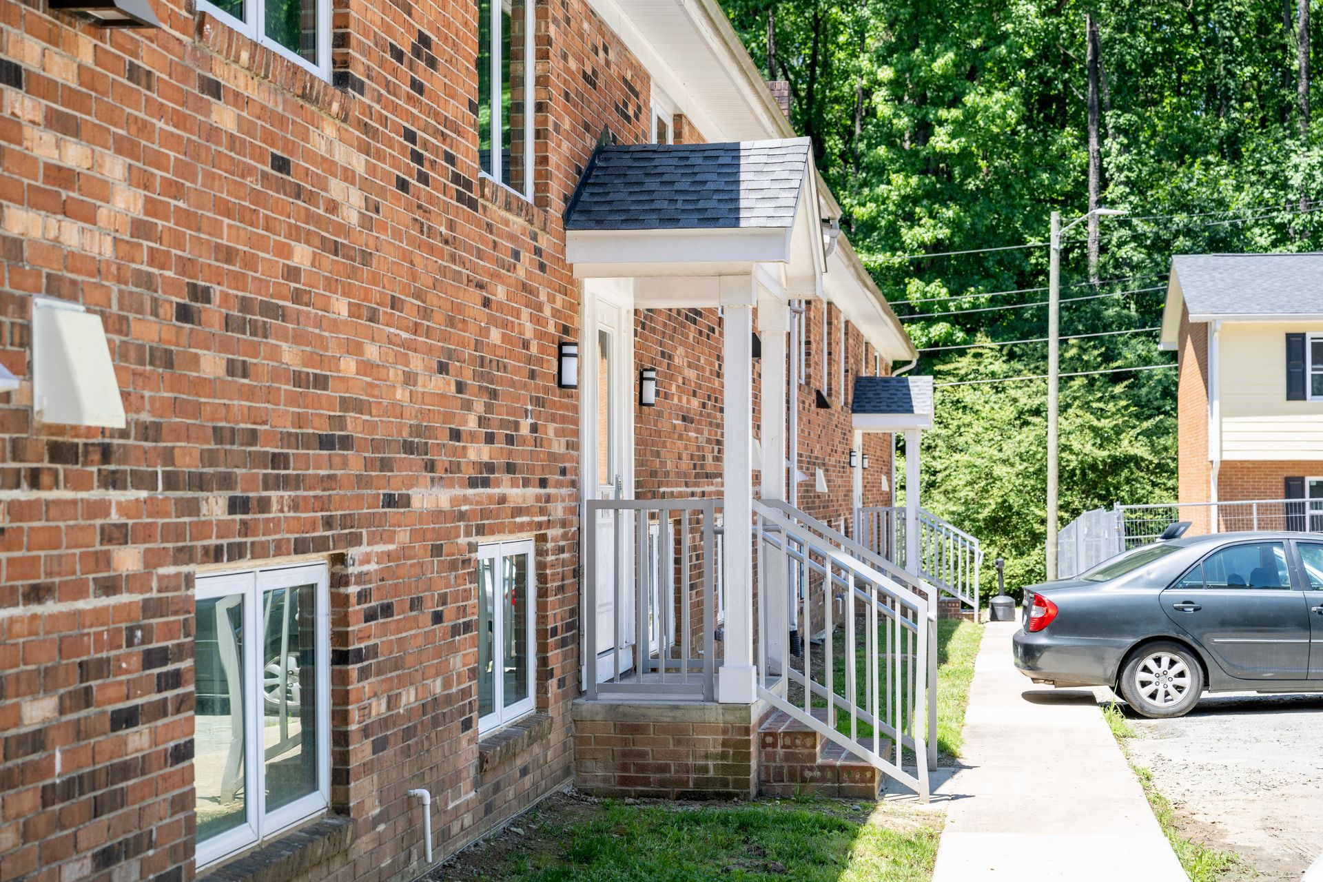 A brick apartment building with a car parked in front of it.