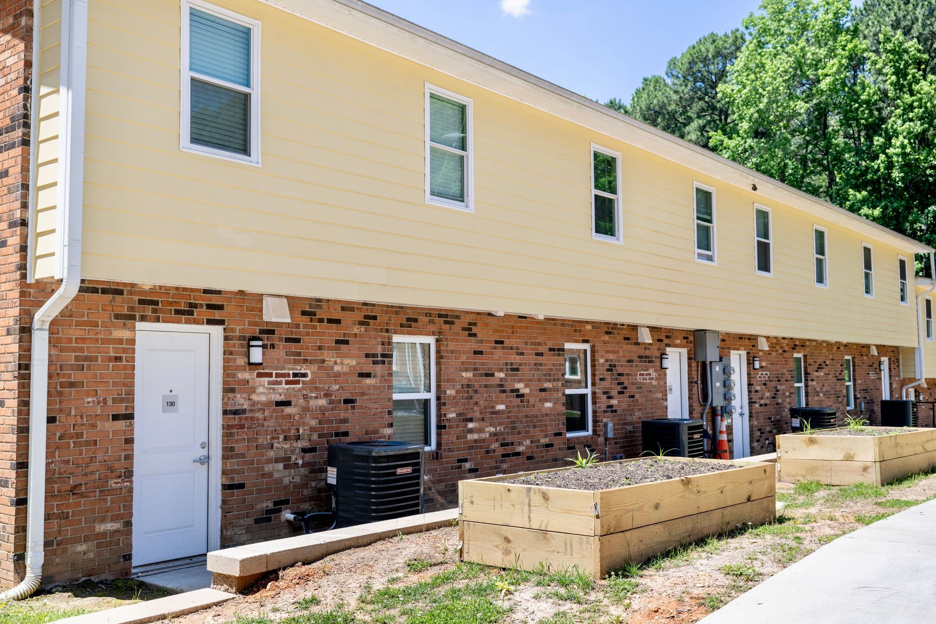 A brick apartment building with a yellow siding and a white door.
