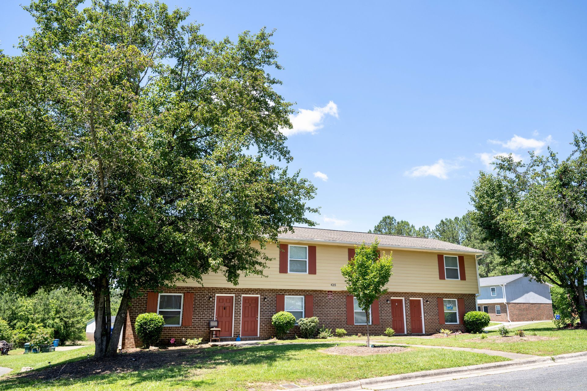 A house with a tree in front of it on a sunny day.