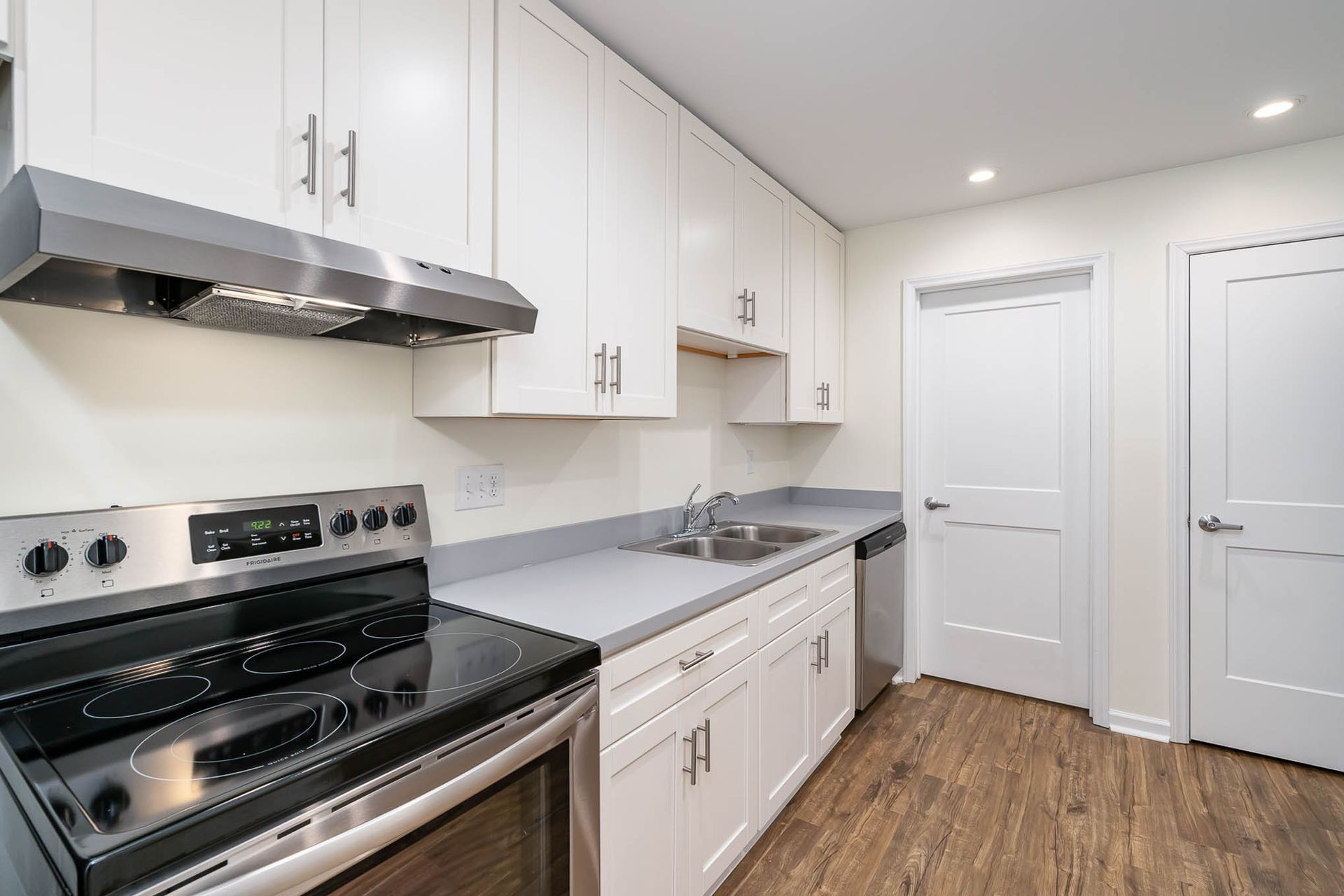 A kitchen with white cabinets , stainless steel appliances , a stove and a sink.