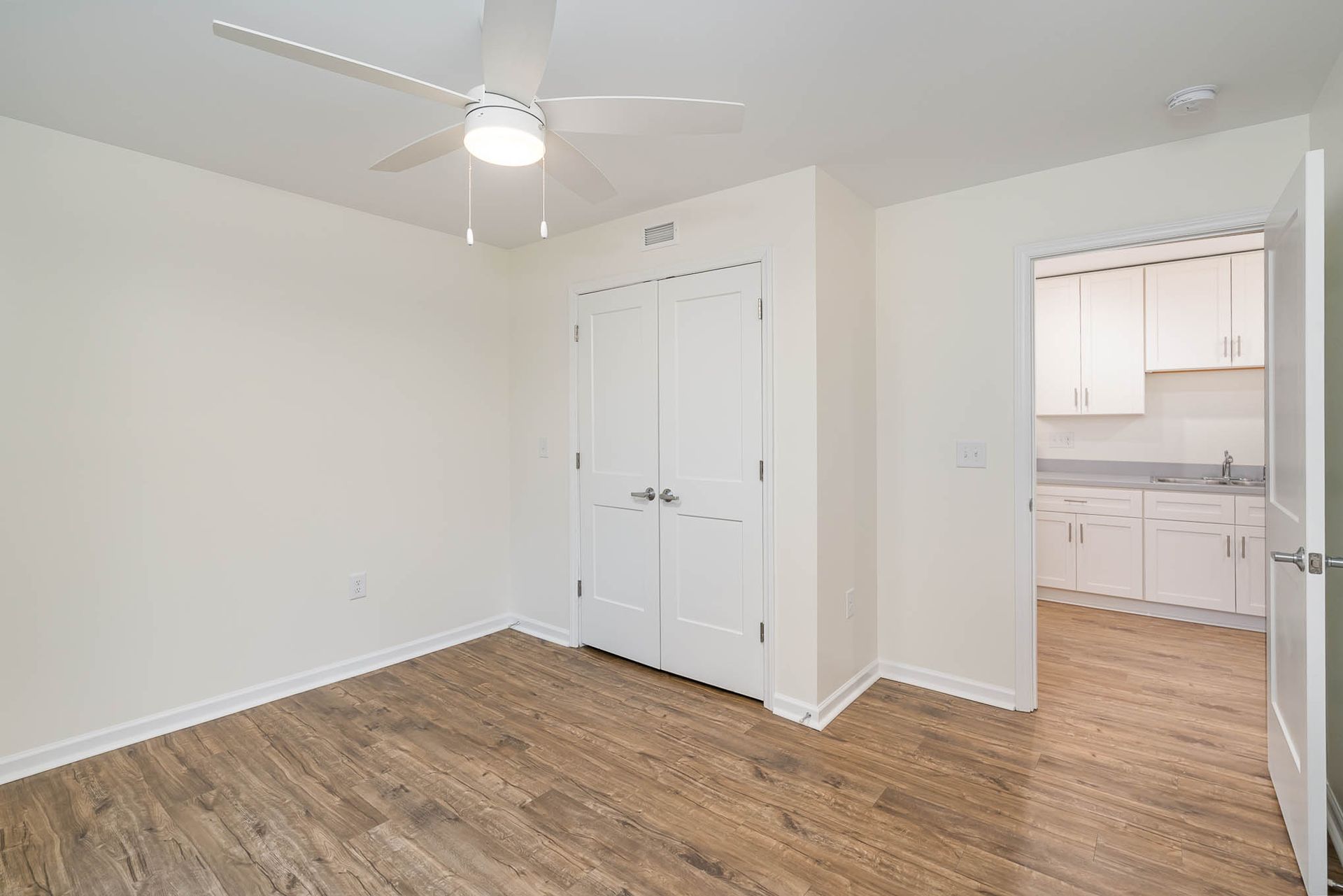 An empty room with hardwood floors and a ceiling fan.