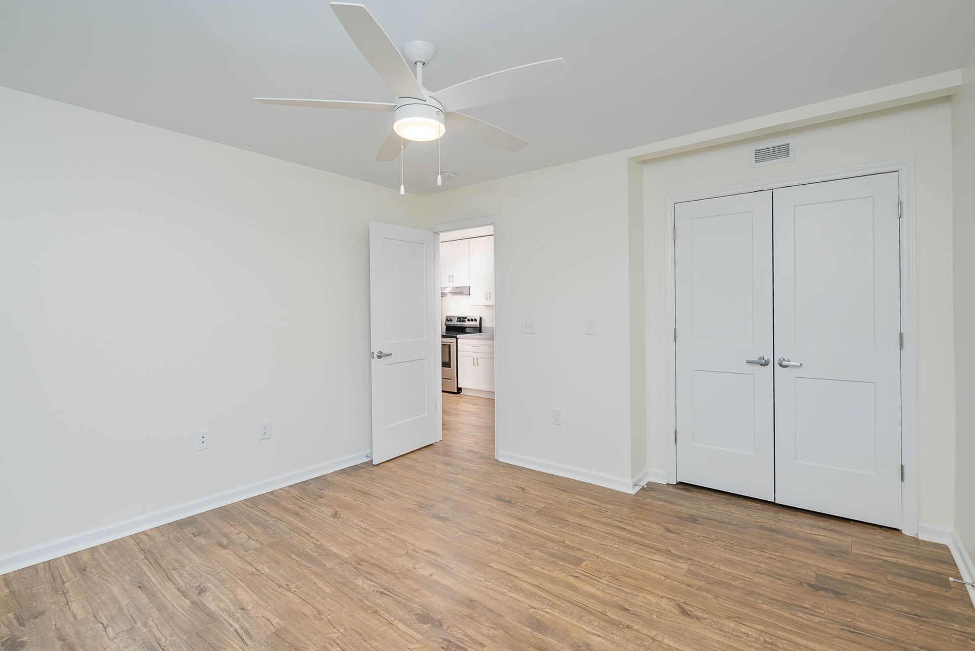 An empty room with hardwood floors and a ceiling fan.