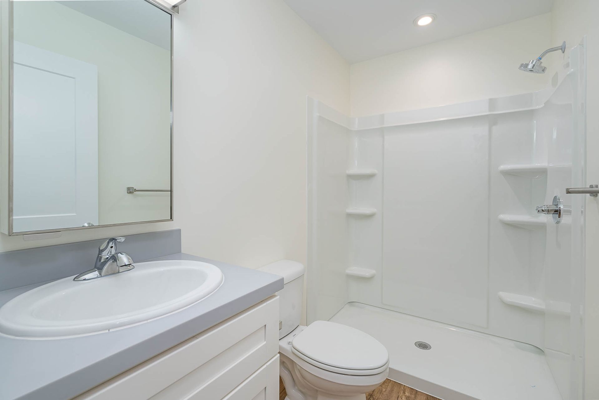 A bathroom with a sink , toilet , shower and mirror.