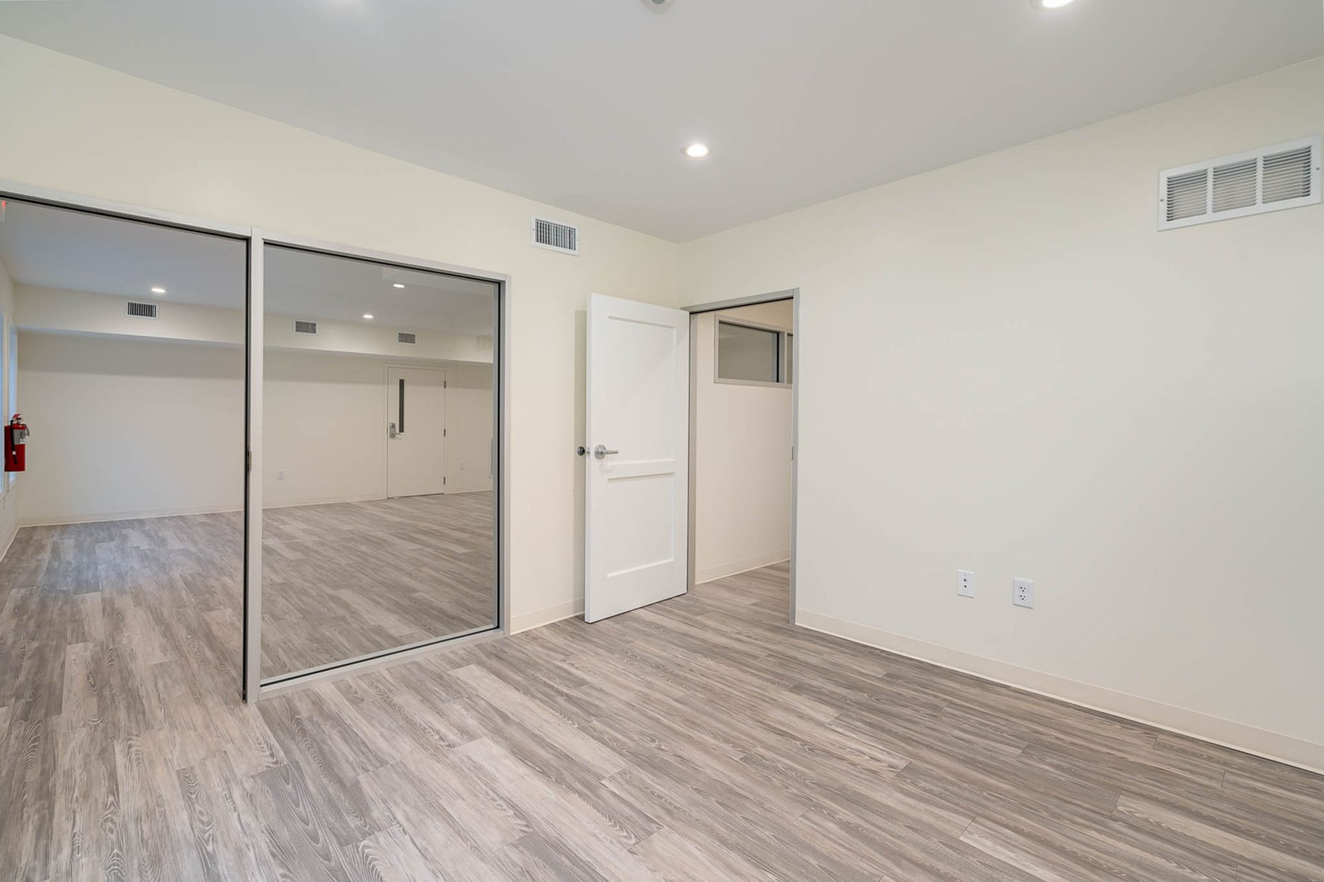 A large empty room with hardwood floors and white walls.