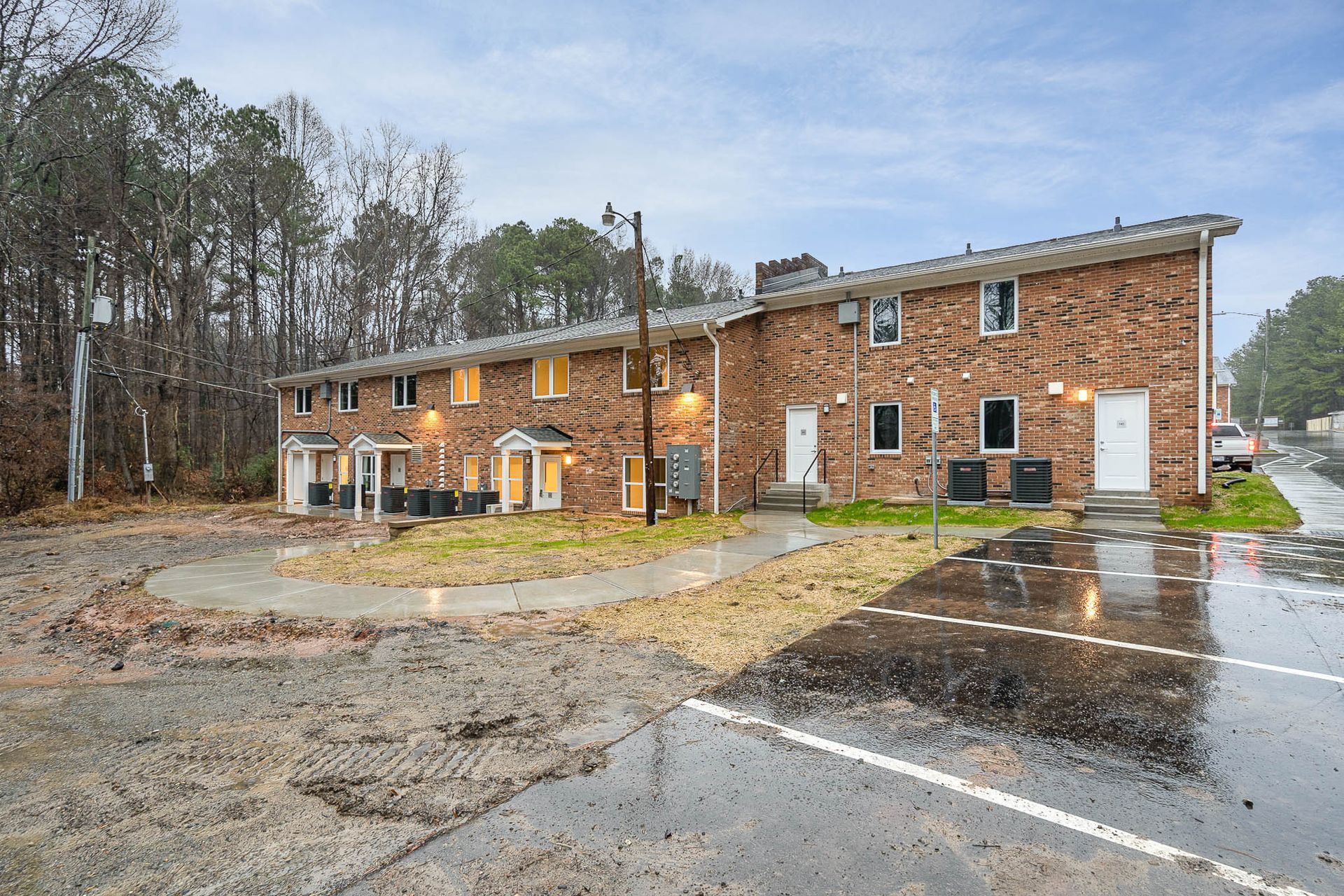 A brick apartment building with a parking lot in front of it.