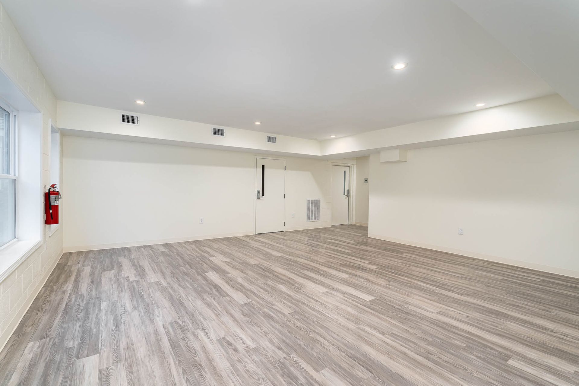 A large empty room with hardwood floors and white walls.