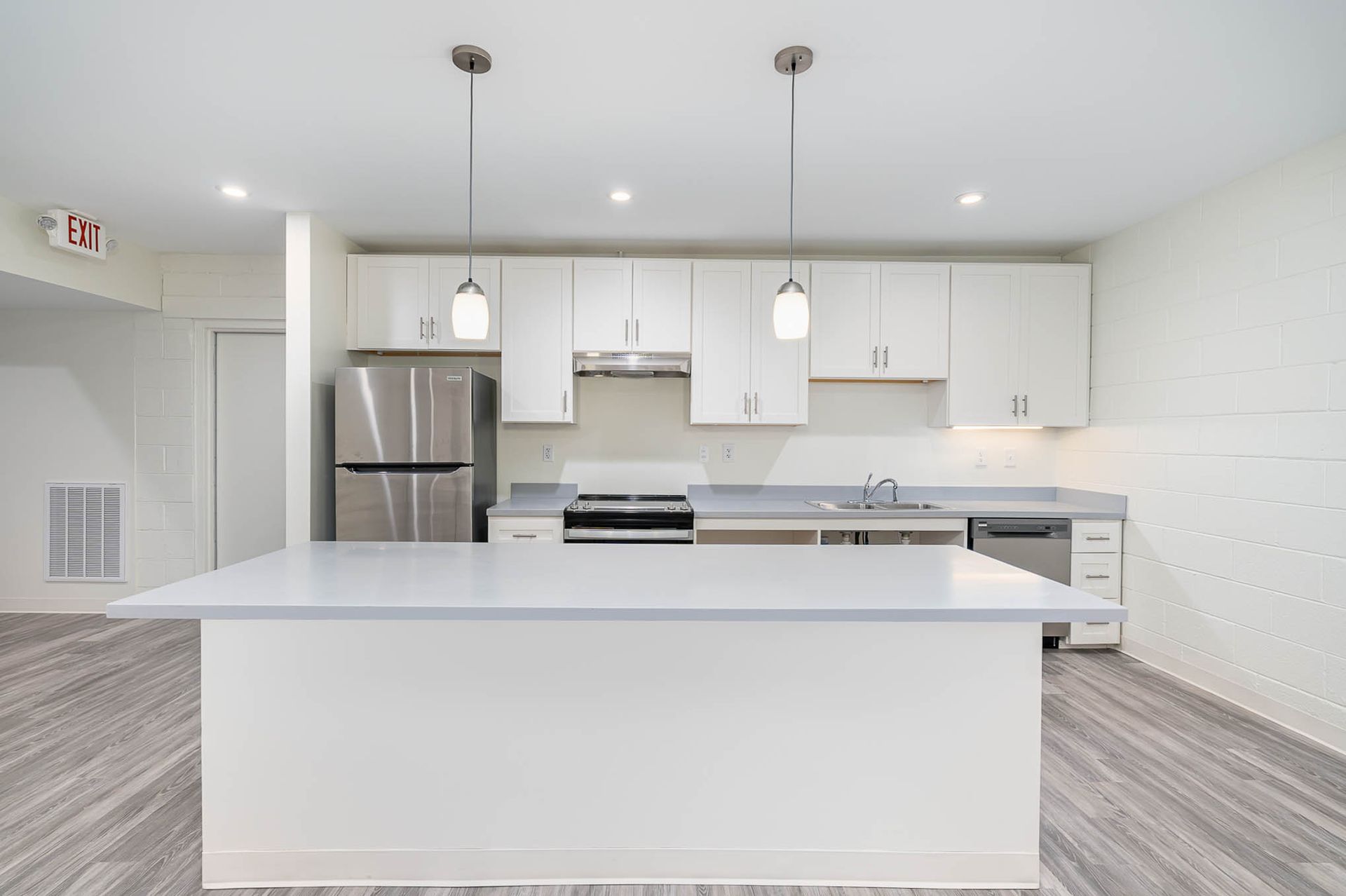 A kitchen with white cabinets , stainless steel appliances , and a large island.