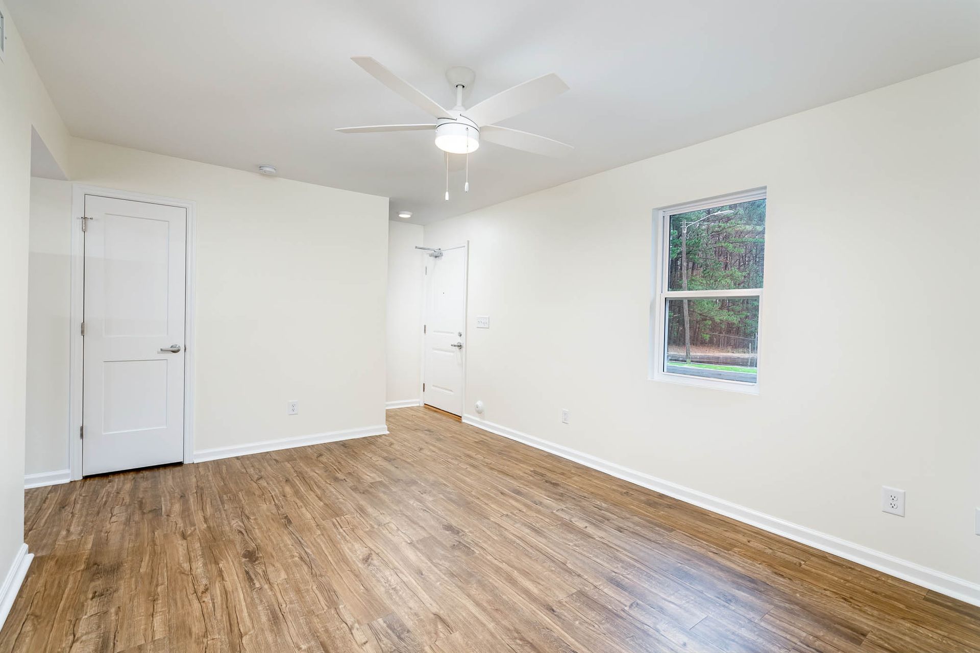 An empty living room with hardwood floors and a ceiling fan.