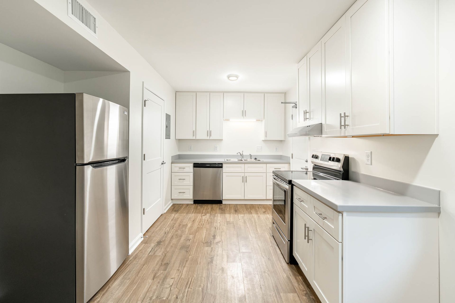 A kitchen with white cabinets , stainless steel appliances , and hardwood floors.