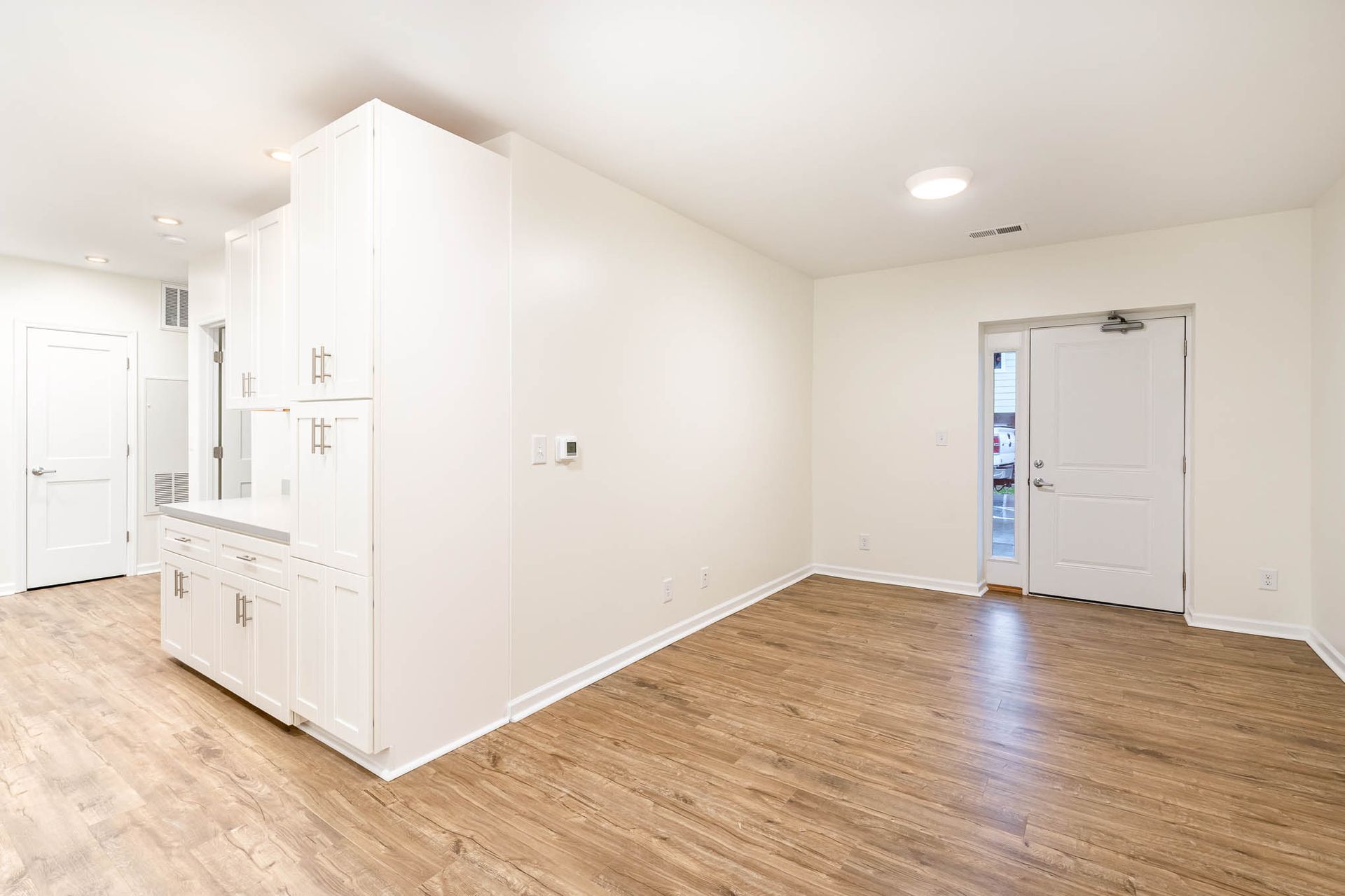 An empty living room with hardwood floors and white walls.