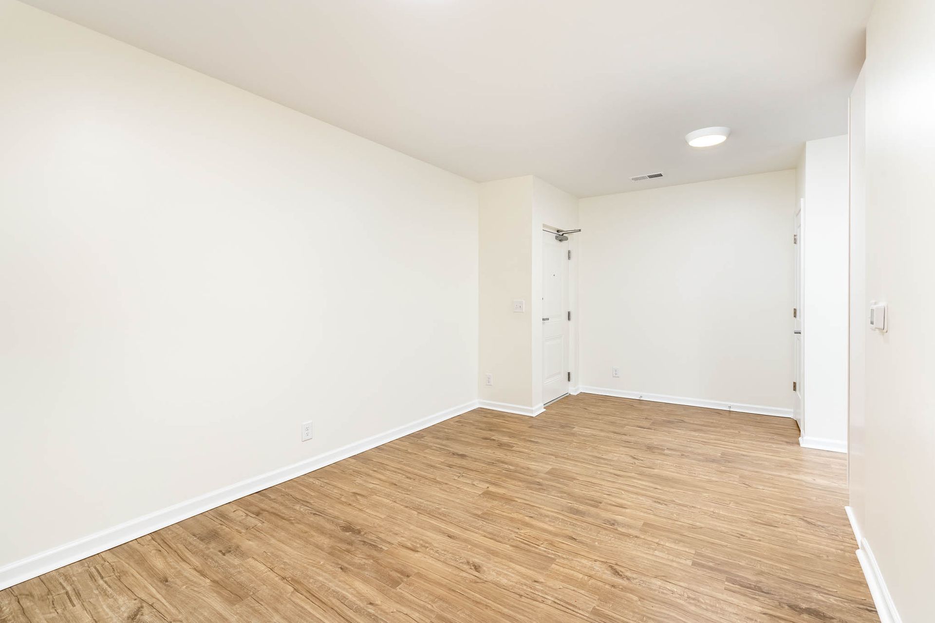 An empty room with hardwood floors and white walls.