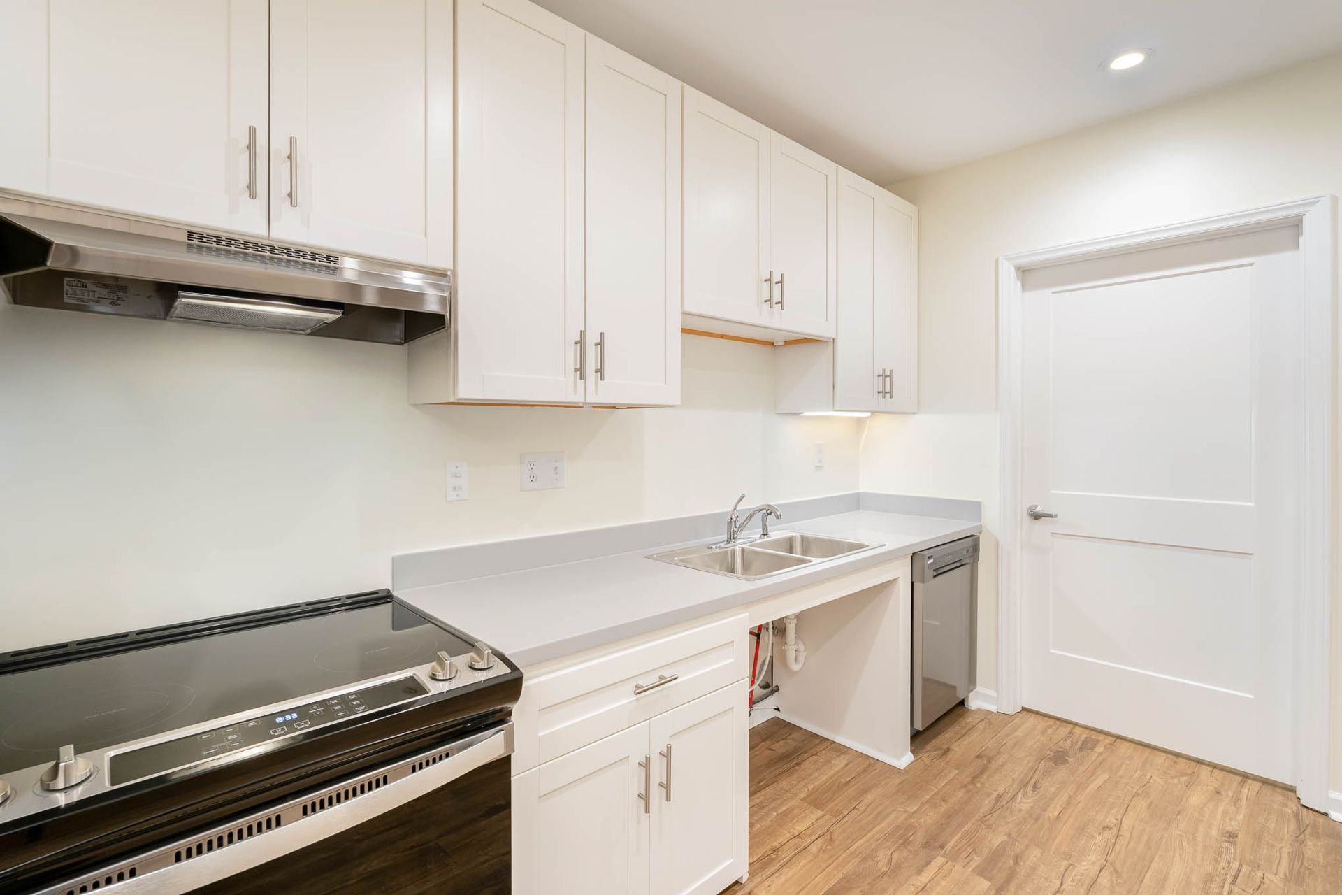 A kitchen with white cabinets , a stove , a sink and a dishwasher.