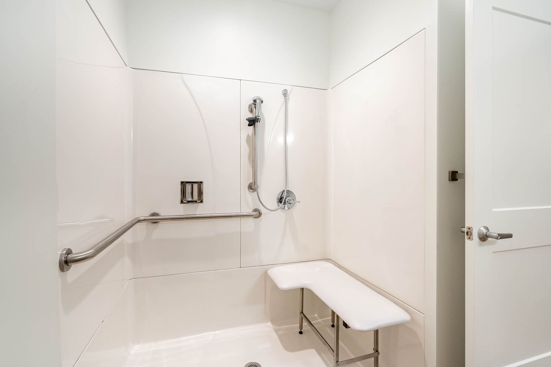 A bathroom with a walk in shower and a bench.
