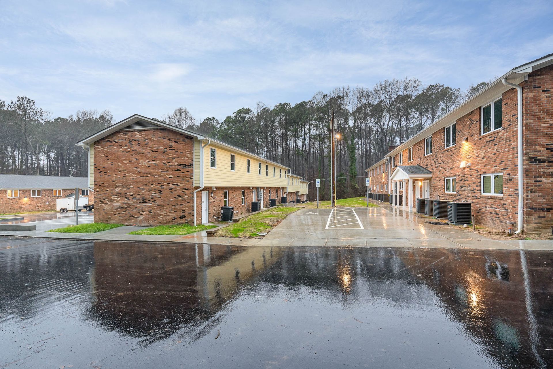 A row of brick apartment buildings with a parking lot in front of them.