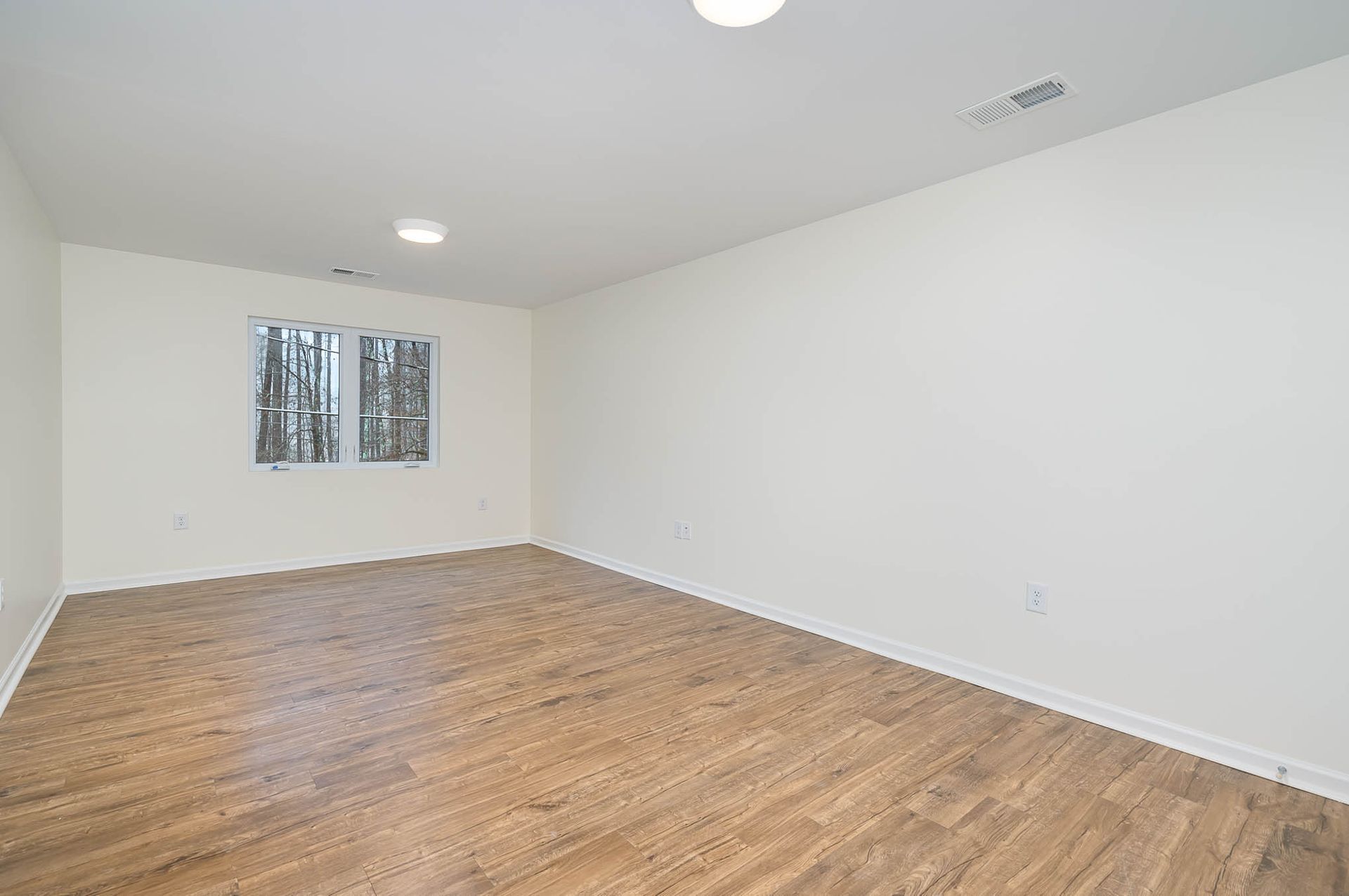 An empty room with hardwood floors and white walls.