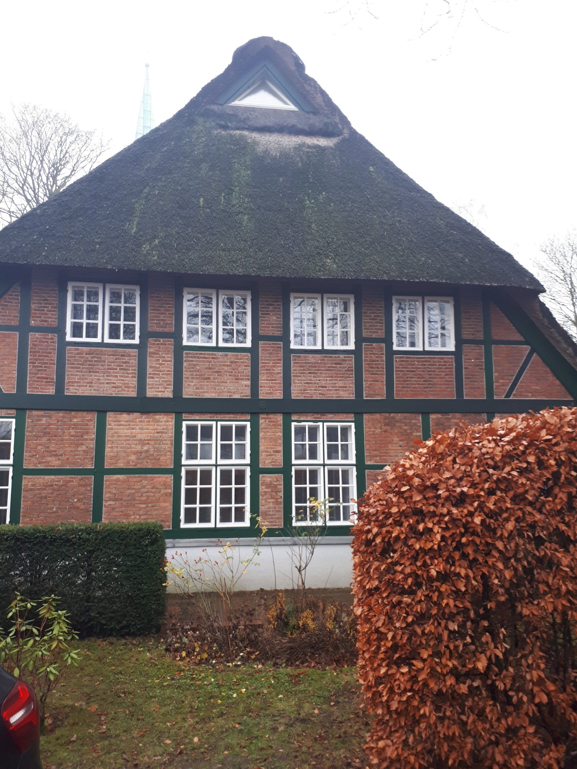 Ein Backsteinhaus mit Strohdach und vielen Fenstern