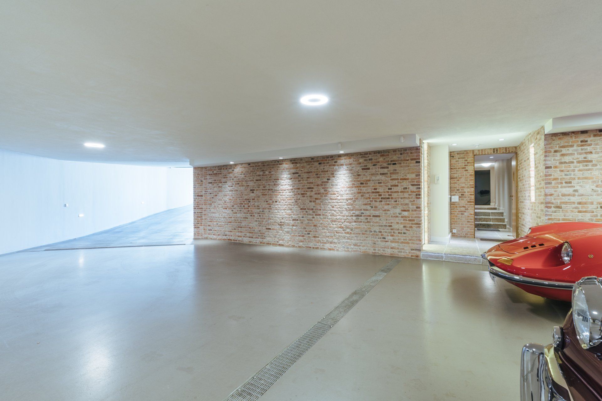 Ein rotes Auto ist in einer Garage mit einer Backsteinmauer geparkt.