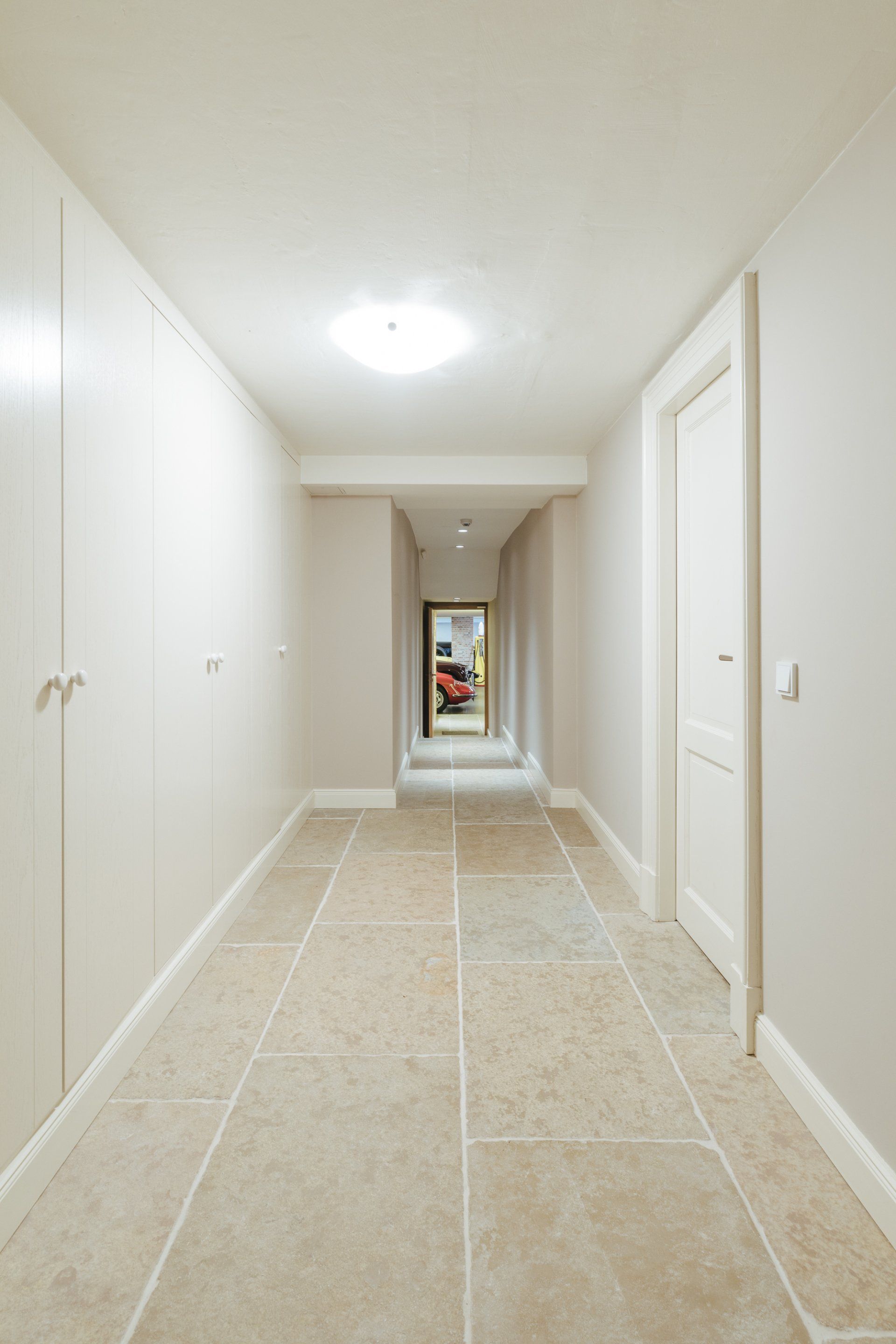 Ein langer Flur mit gefliestem Boden und weißen Wänden