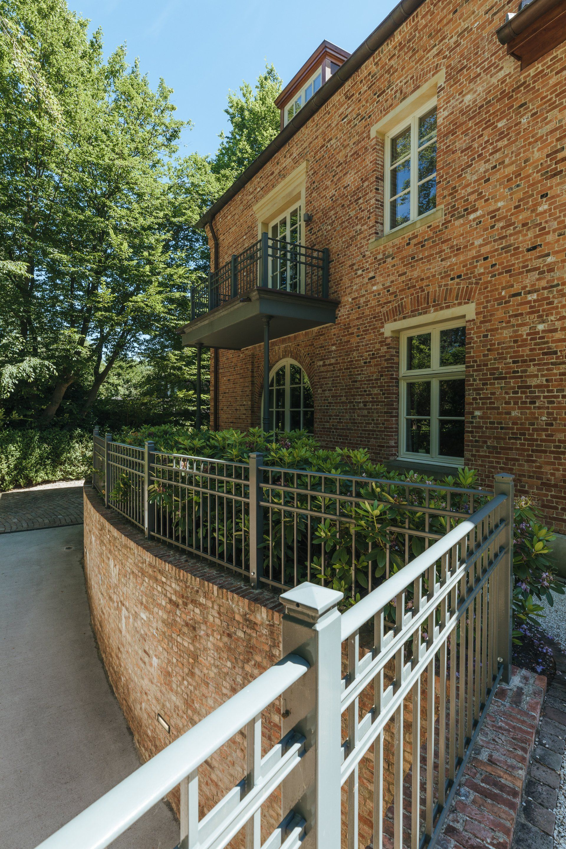 Ein Backsteingebäude mit einem Balkon und einem weißen Zaun
