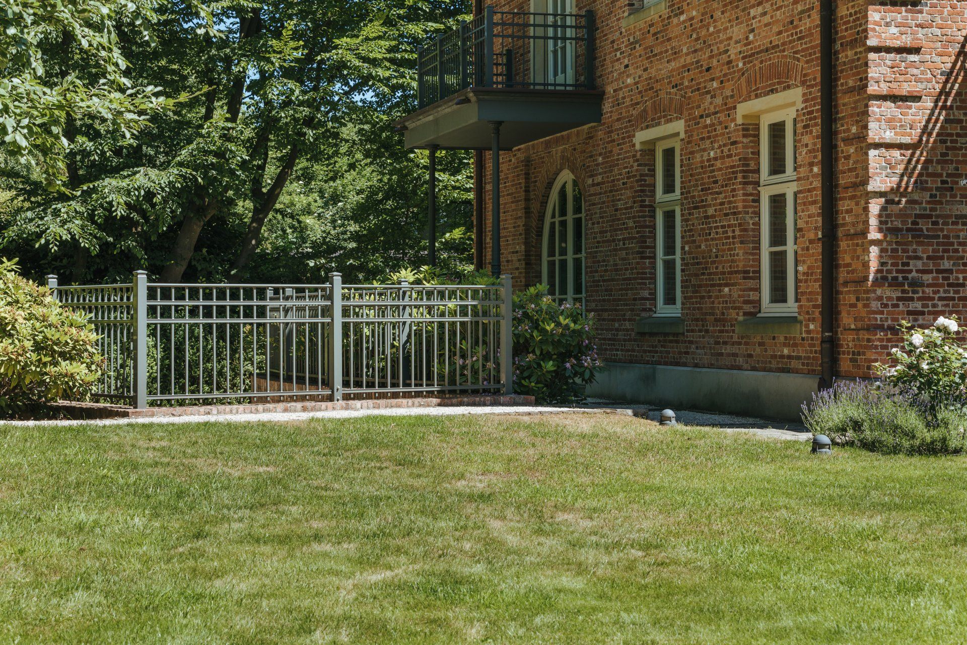 Ein großes Backsteinhaus mit einem üppigen grünen Rasen davor.
