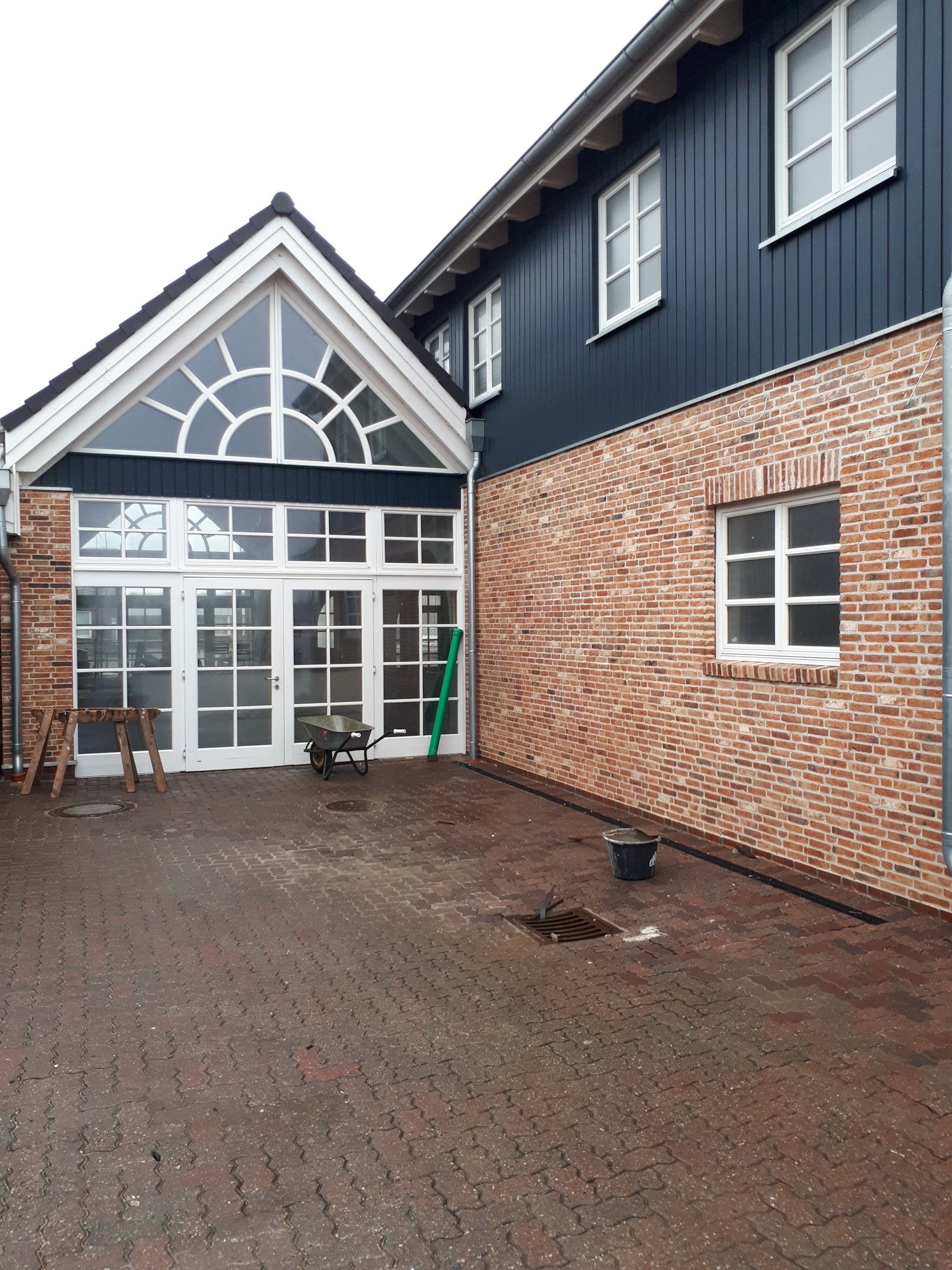 Ein Backsteingebäude mit blauer Außenverkleidung und weißen Fenstern