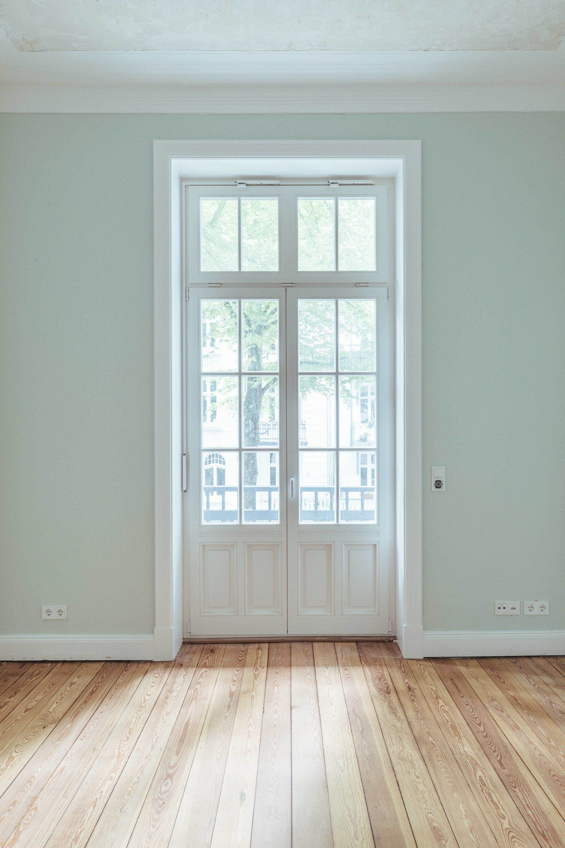 Ein leerer Raum mit Holzboden und großem Fenster.