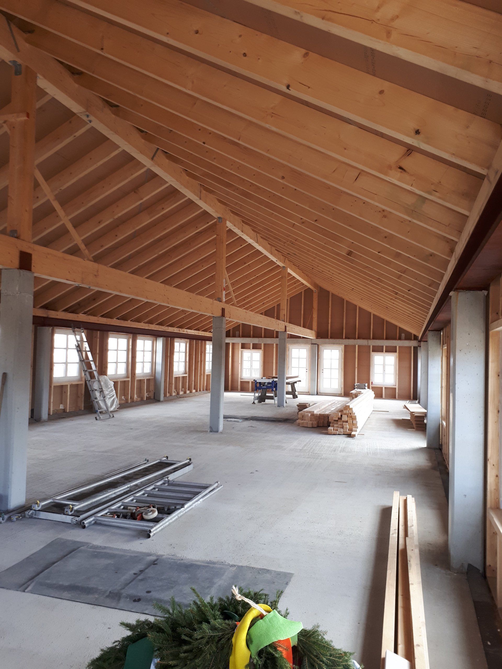 Ein großer leerer Raum mit Holzbalken und einem Kranz auf dem Boden