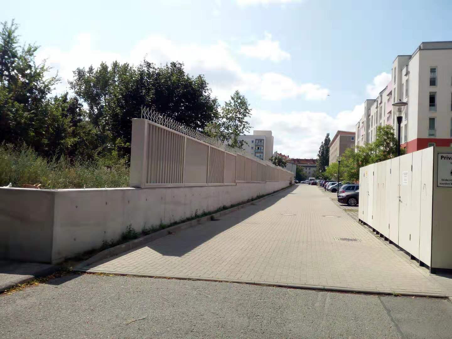 Eine Straße mit einem Zaun und einem Gebäude im Hintergrund