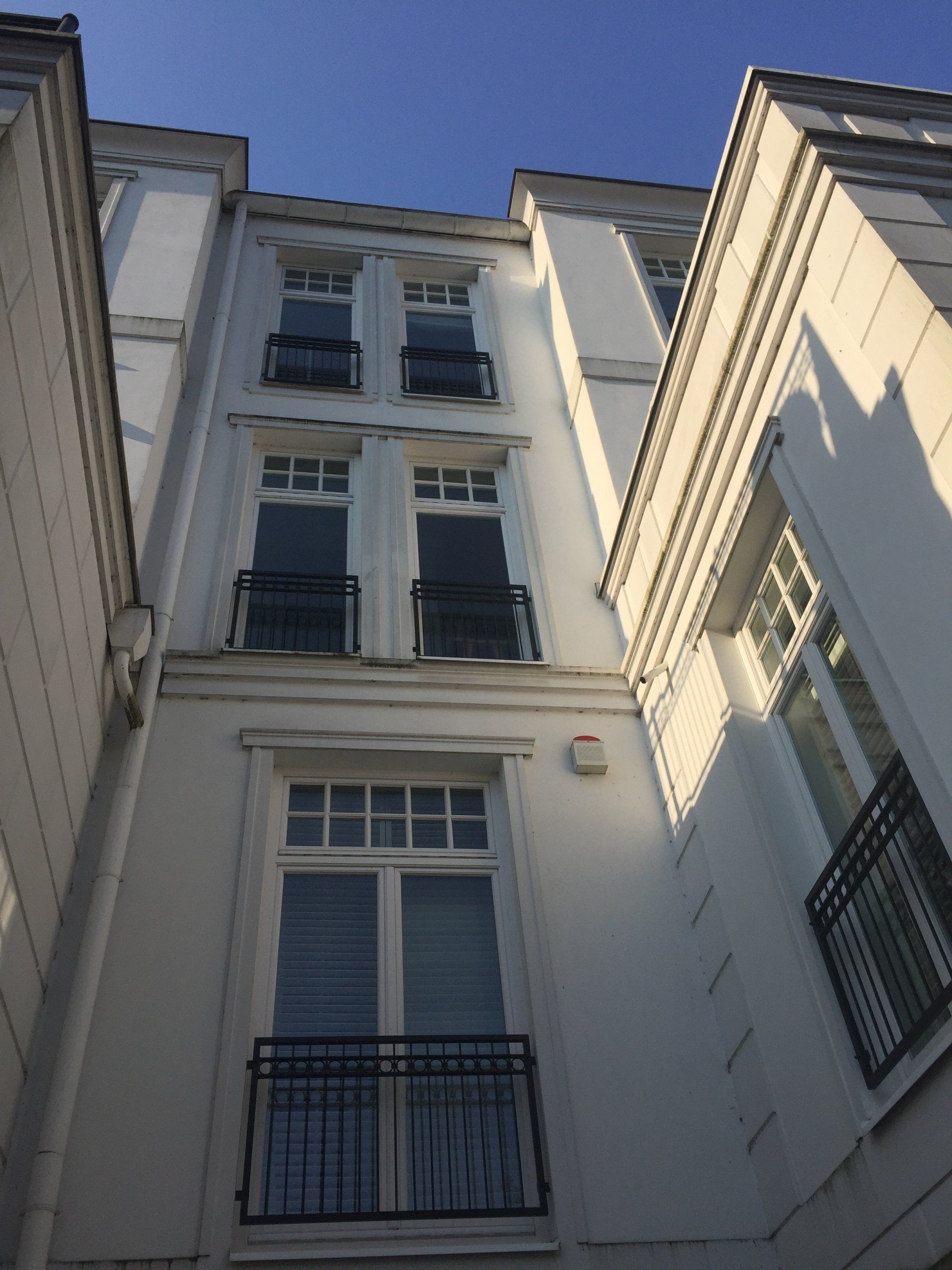 Blick nach oben auf ein weißes Gebäude mit einem Balkon