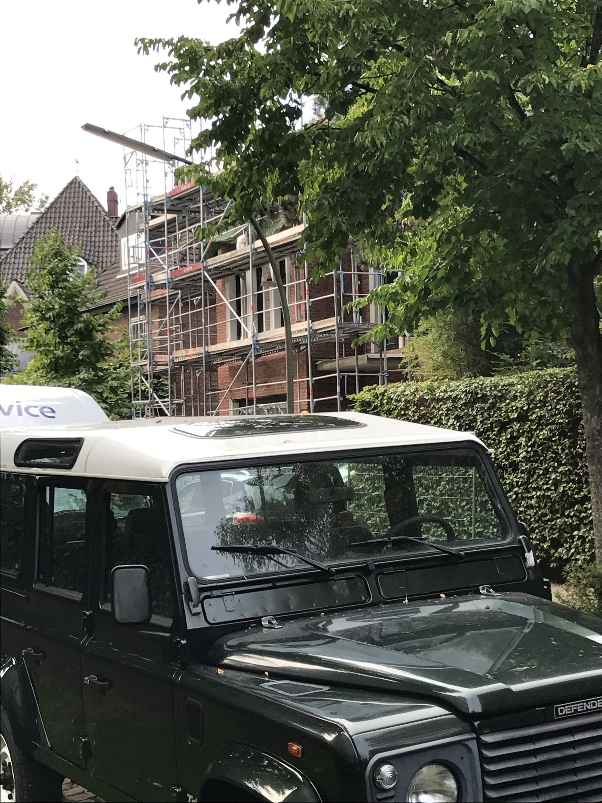 Ein schwarzer Land Rover Defender steht vor einem im Bau befindlichen Gebäude.