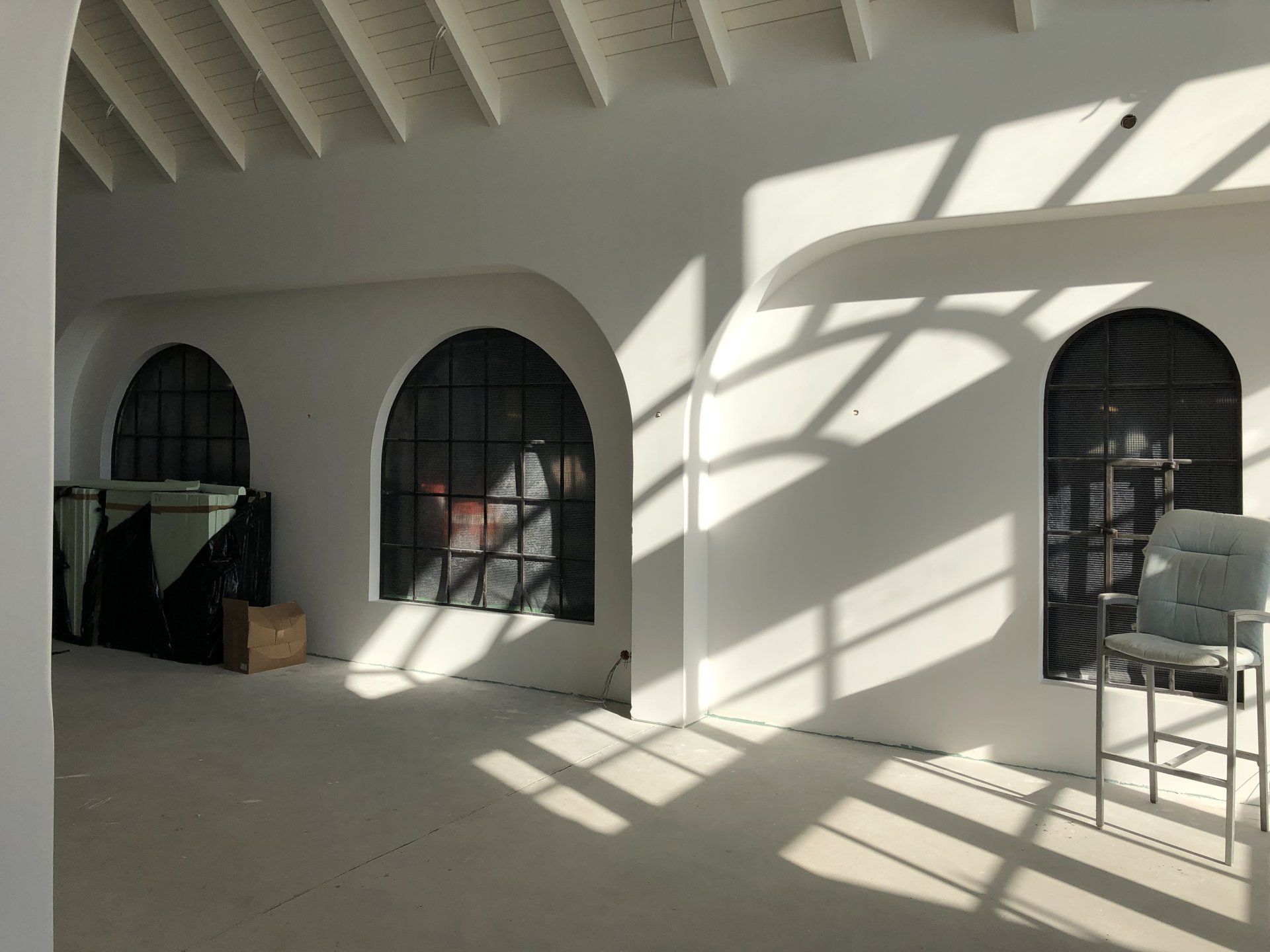 Ein weißer Raum mit Bogenfenstern und einem Stuhl