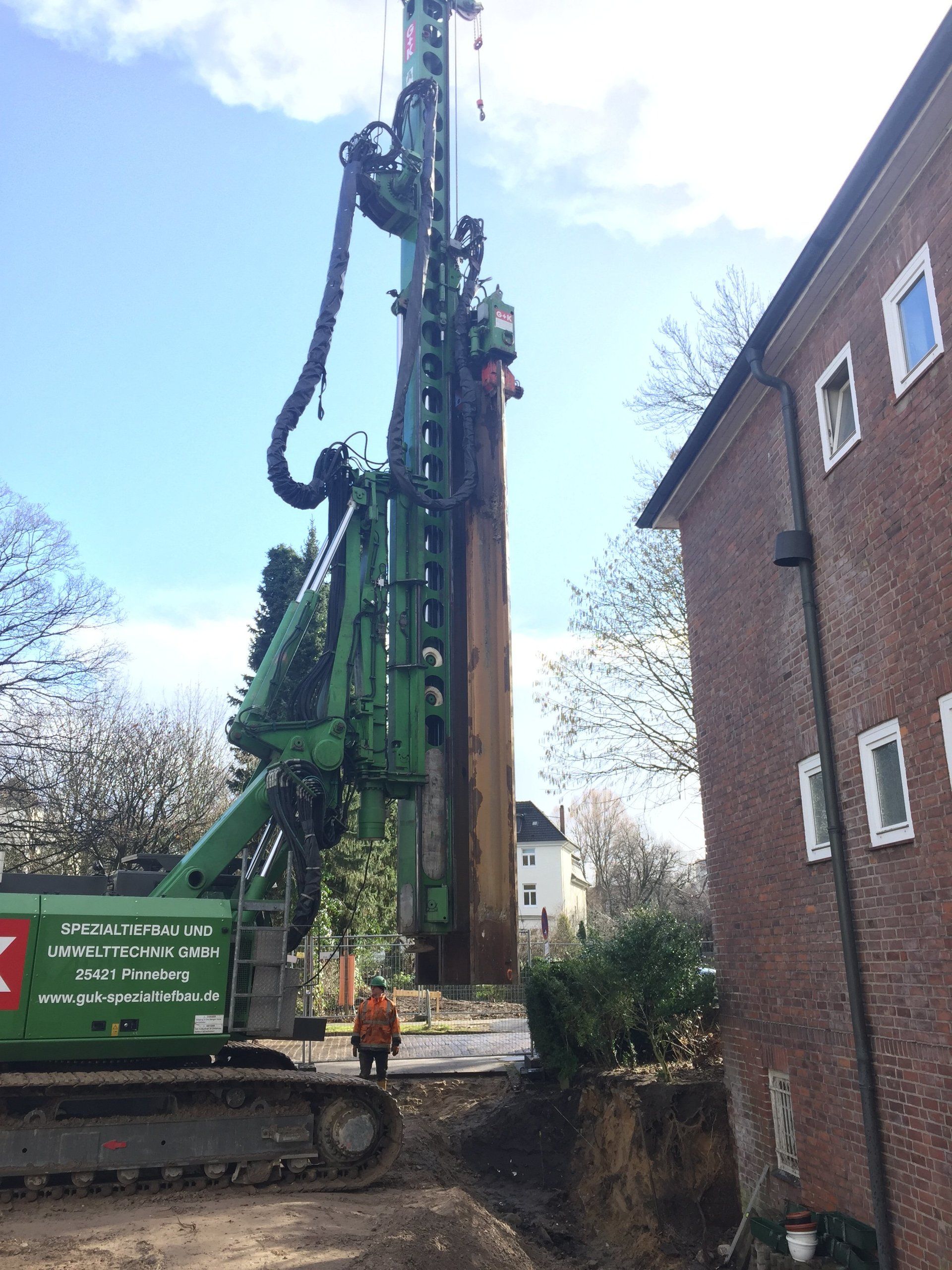 Eine große grüne Maschine steht vor einem Backsteingebäude.