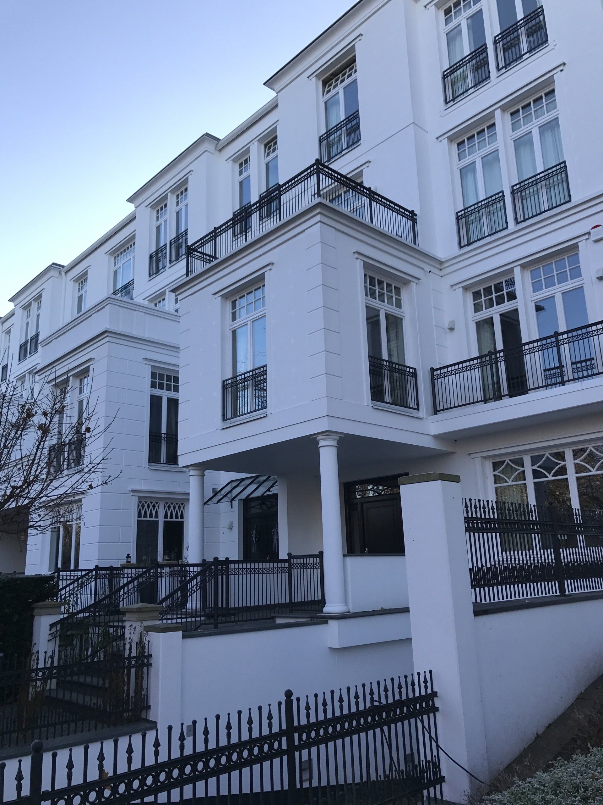 Ein großes weißes Gebäude mit Balkonen und einem Zaun