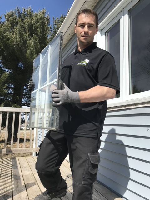 Un homme tient un morceau de verre devant une maison