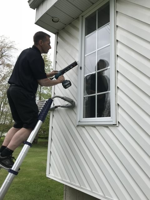 Un homme debout sur une échelle nettoyant une fenêtre