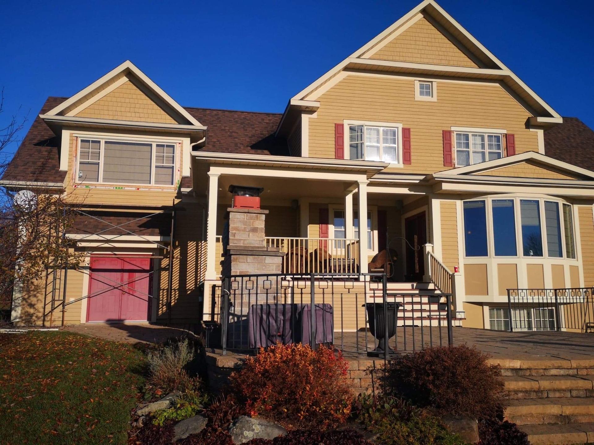 Une grande maison jaune avec une porte de garage rouge