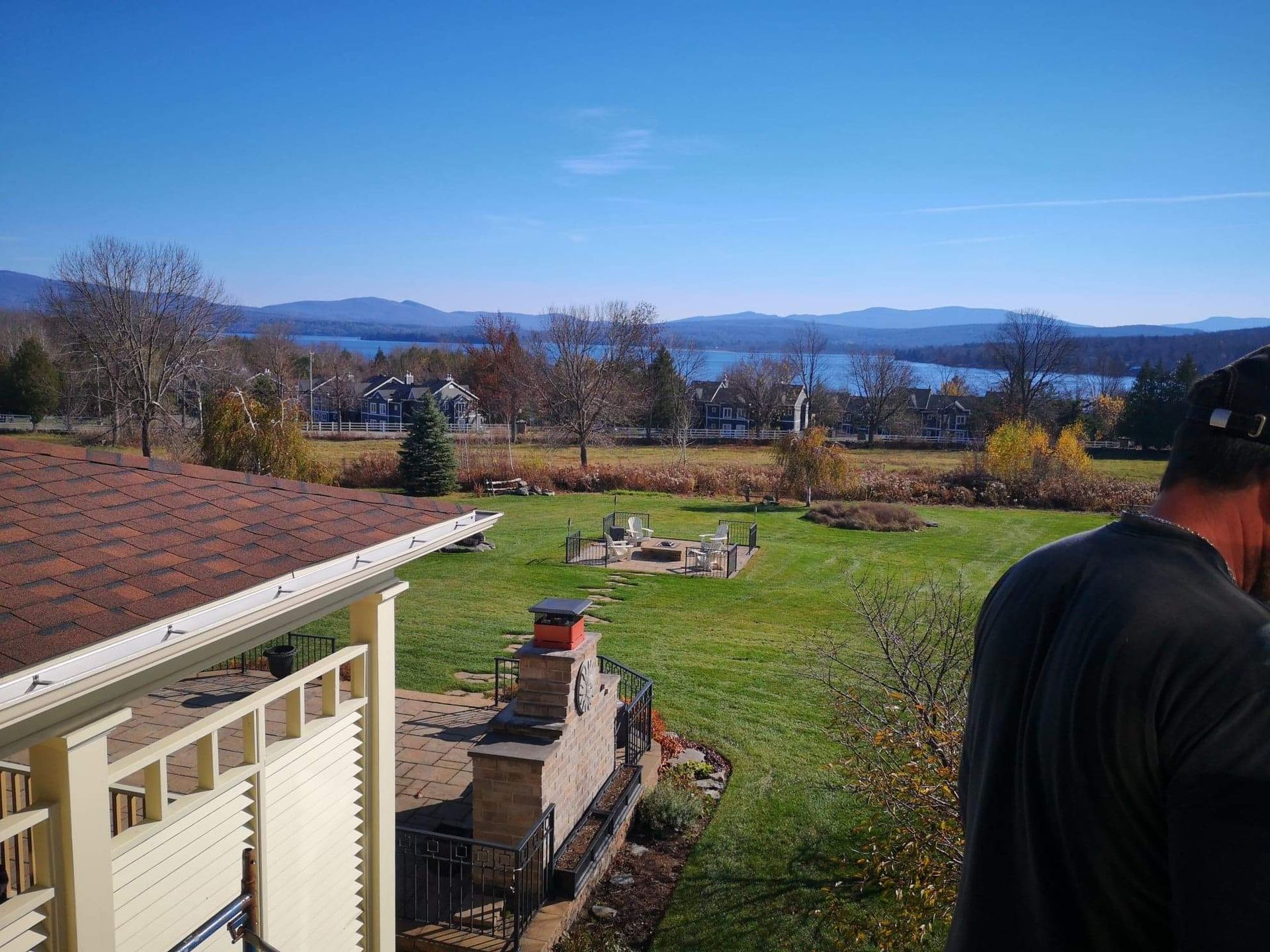 Un homme se tient devant une maison avec vue sur un lac.