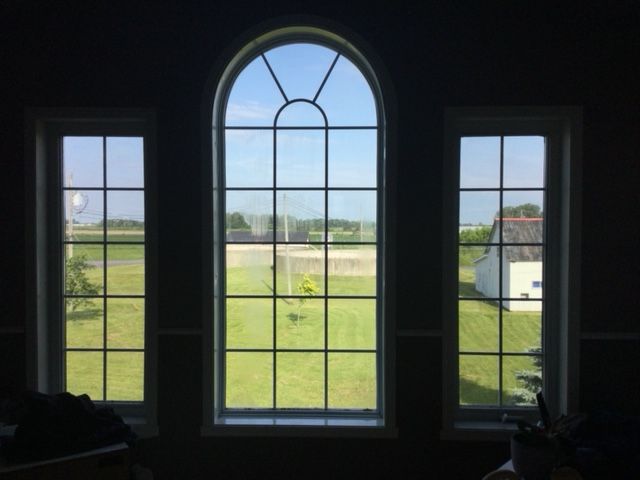 Trois fenêtres cintrées avec vue sur un champ