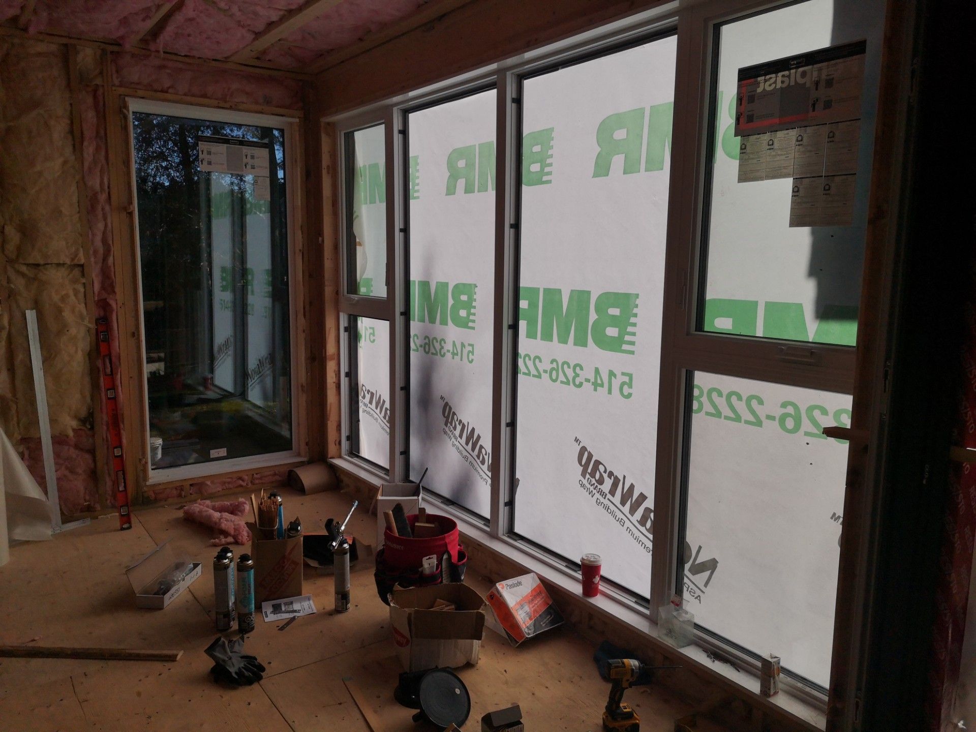 Une pièce avec beaucoup de fenêtres et des outils au sol.