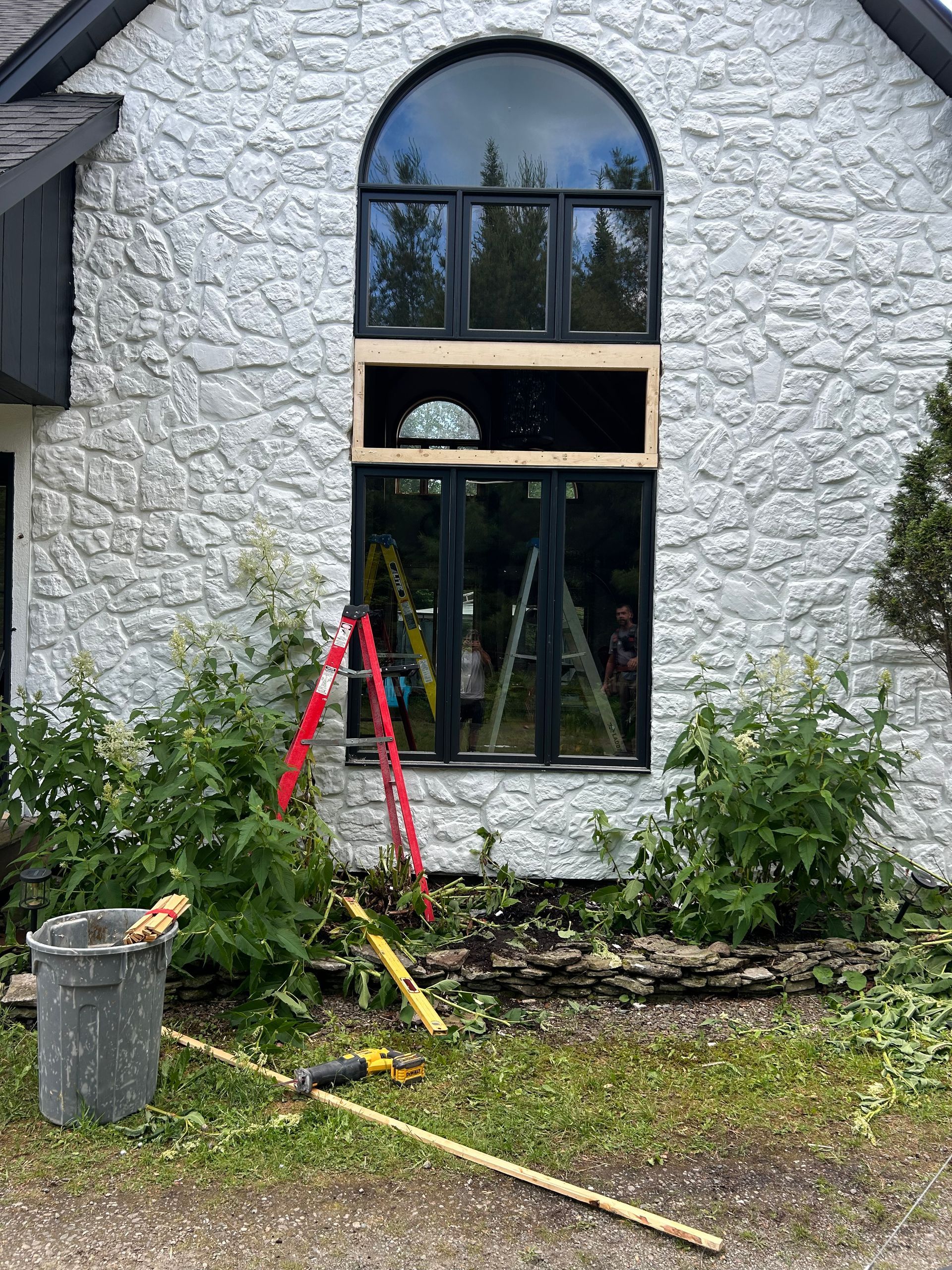 Une grande fenêtre est en train d'être installée sur la façade d'une maison.