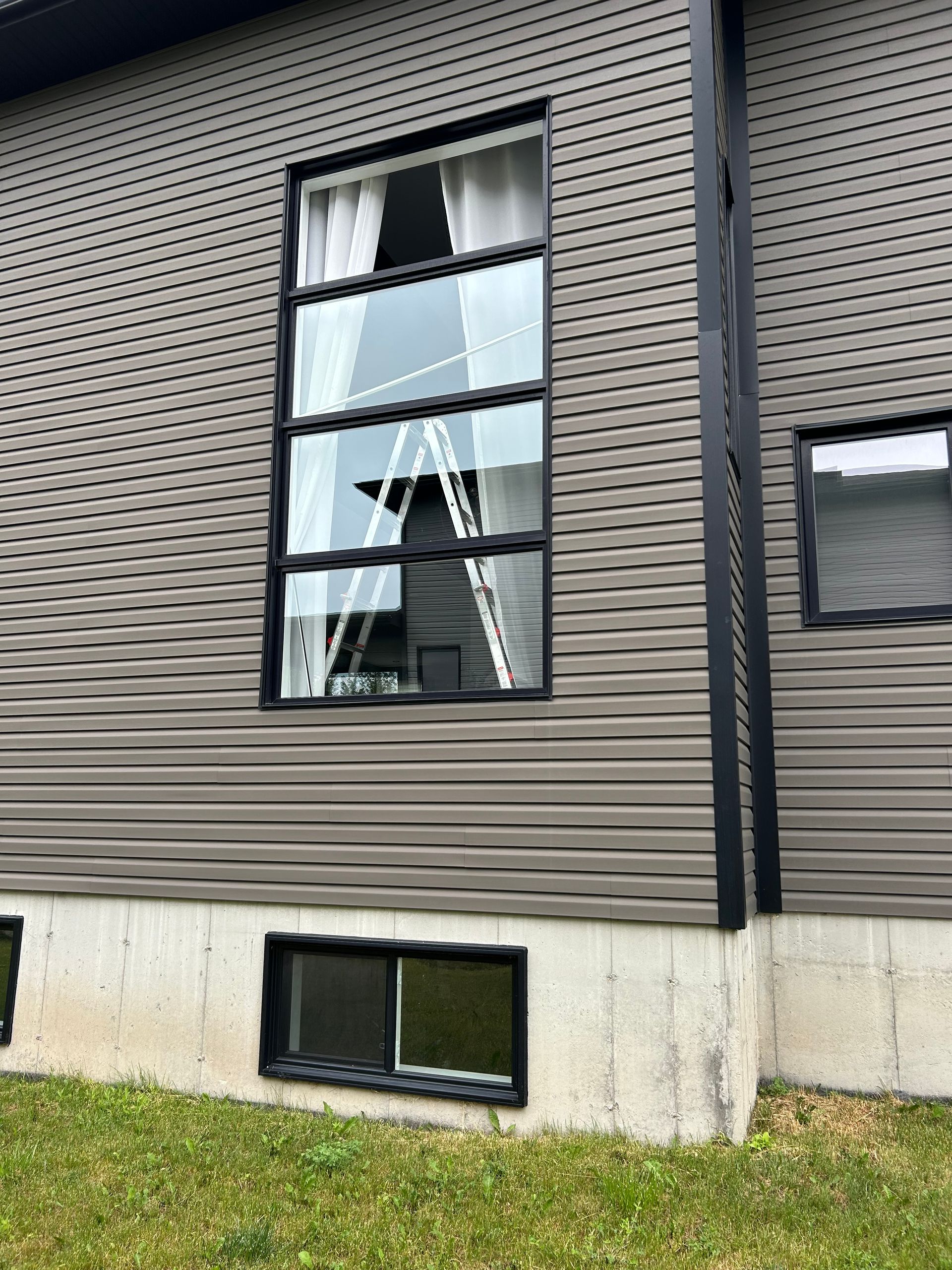 Une maison avec une échelle dans la fenêtre et une fenêtre cassée.