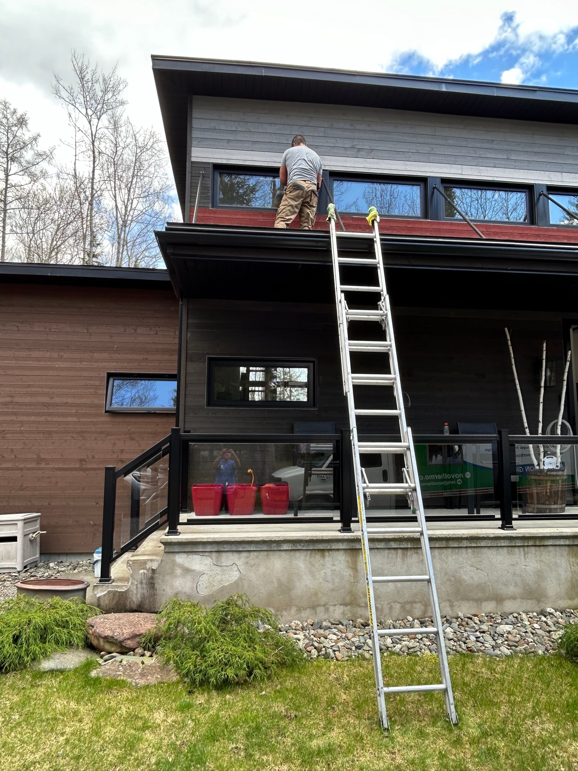 Un homme peint le toit d'une maison avec une échelle.