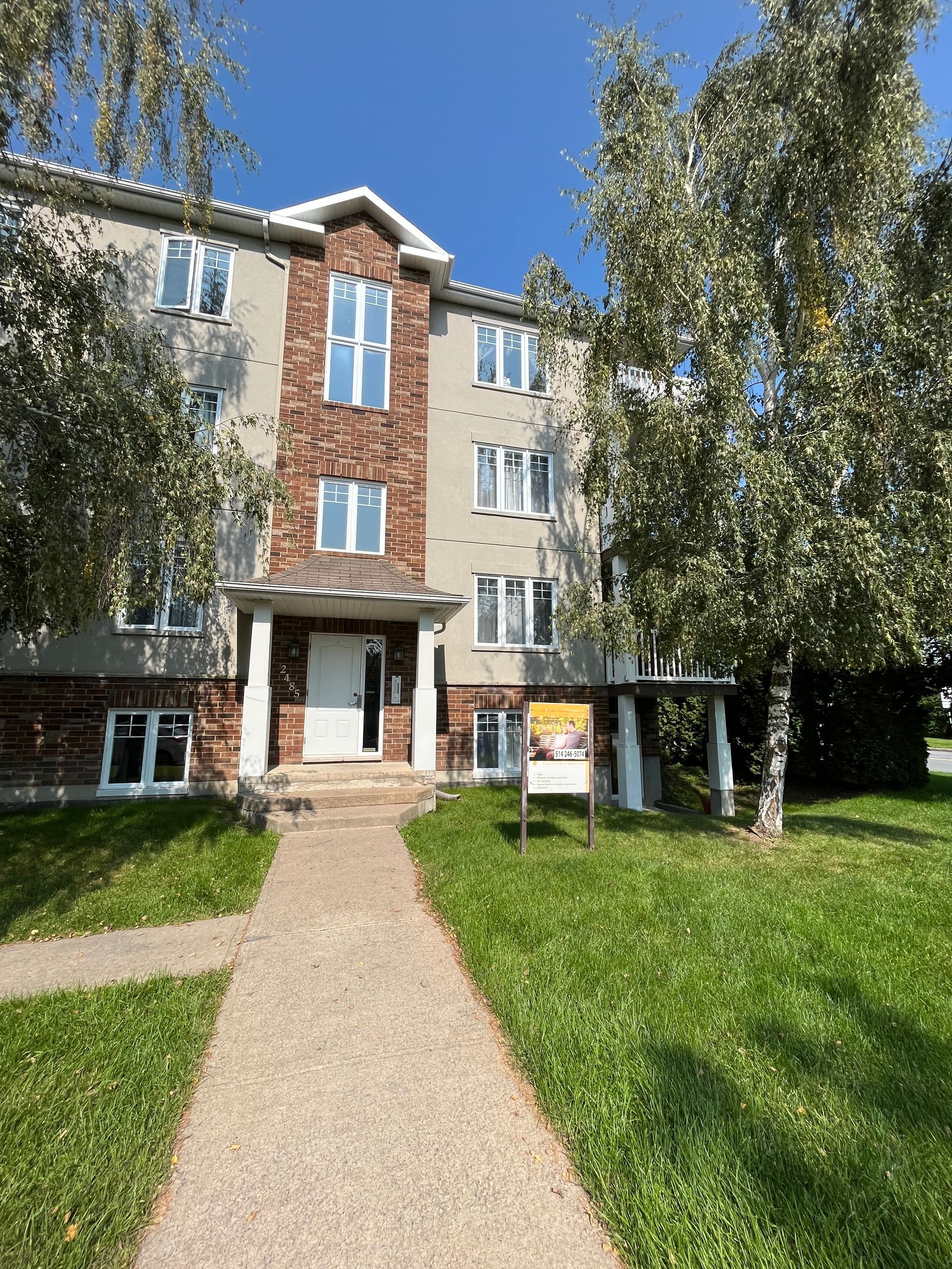 Un grand immeuble d'appartements avec une enseigne devant.