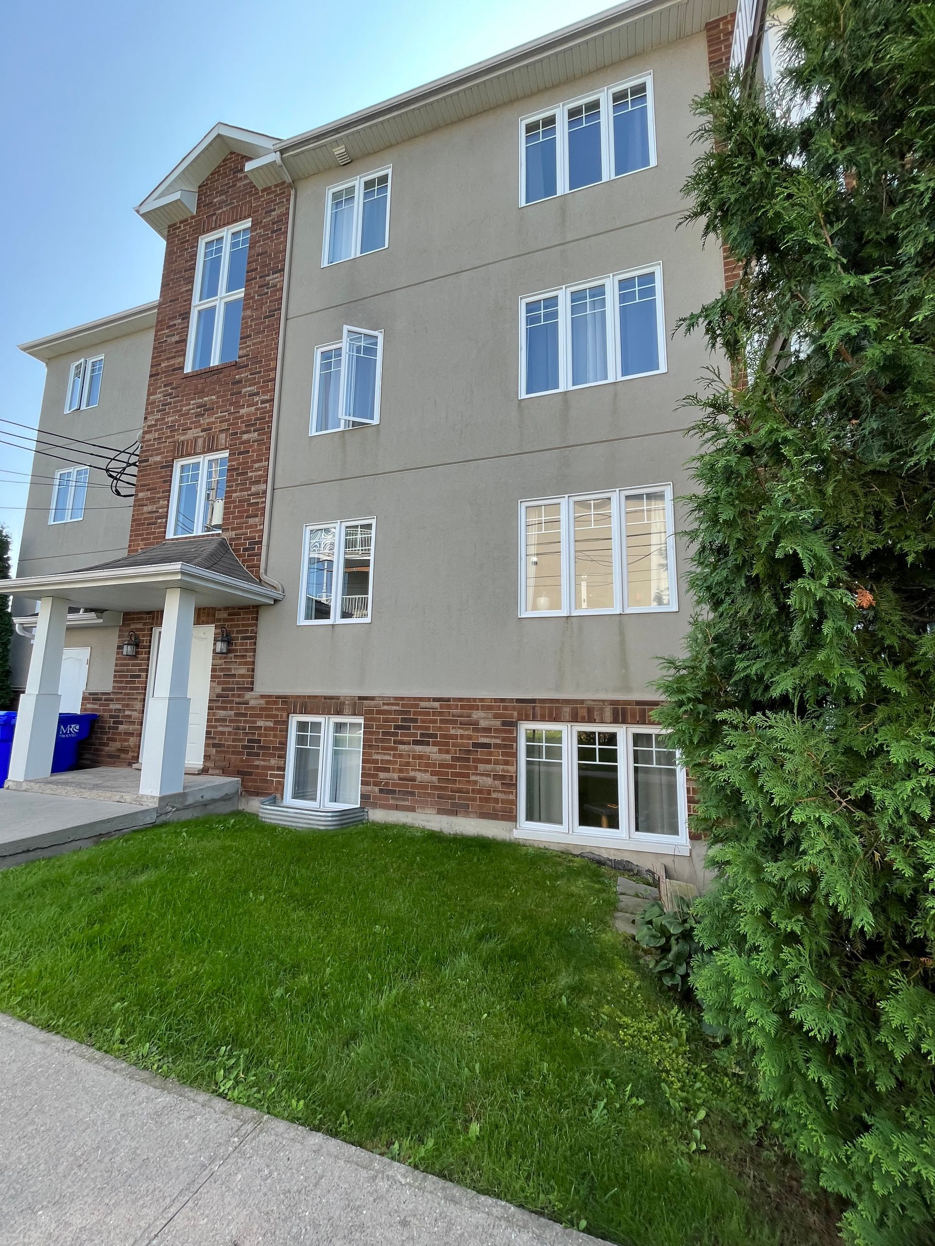 Un grand bâtiment avec beaucoup de fenêtres et un arbre devant lui