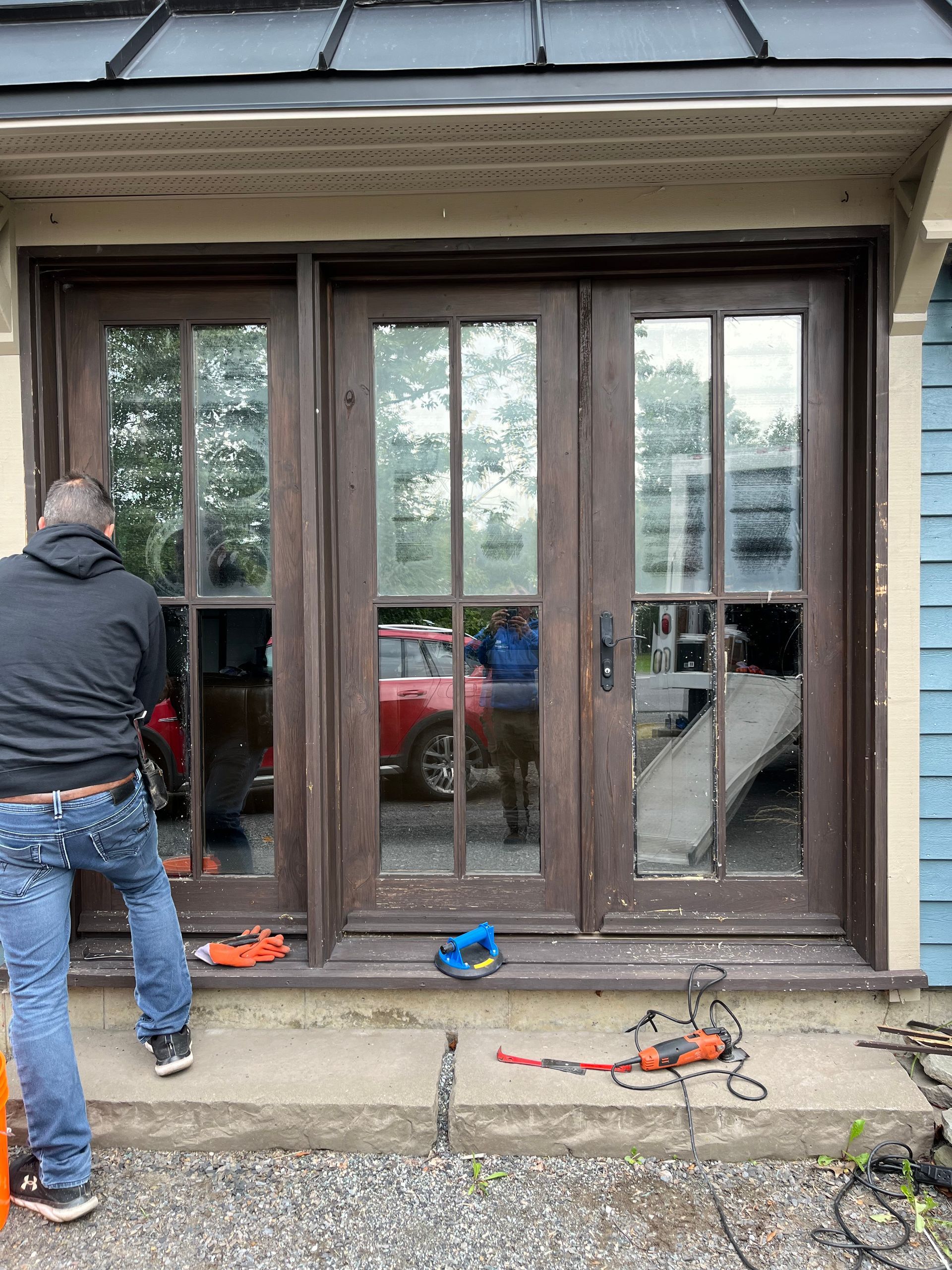 Un homme se tient devant une porte coulissante en verre.