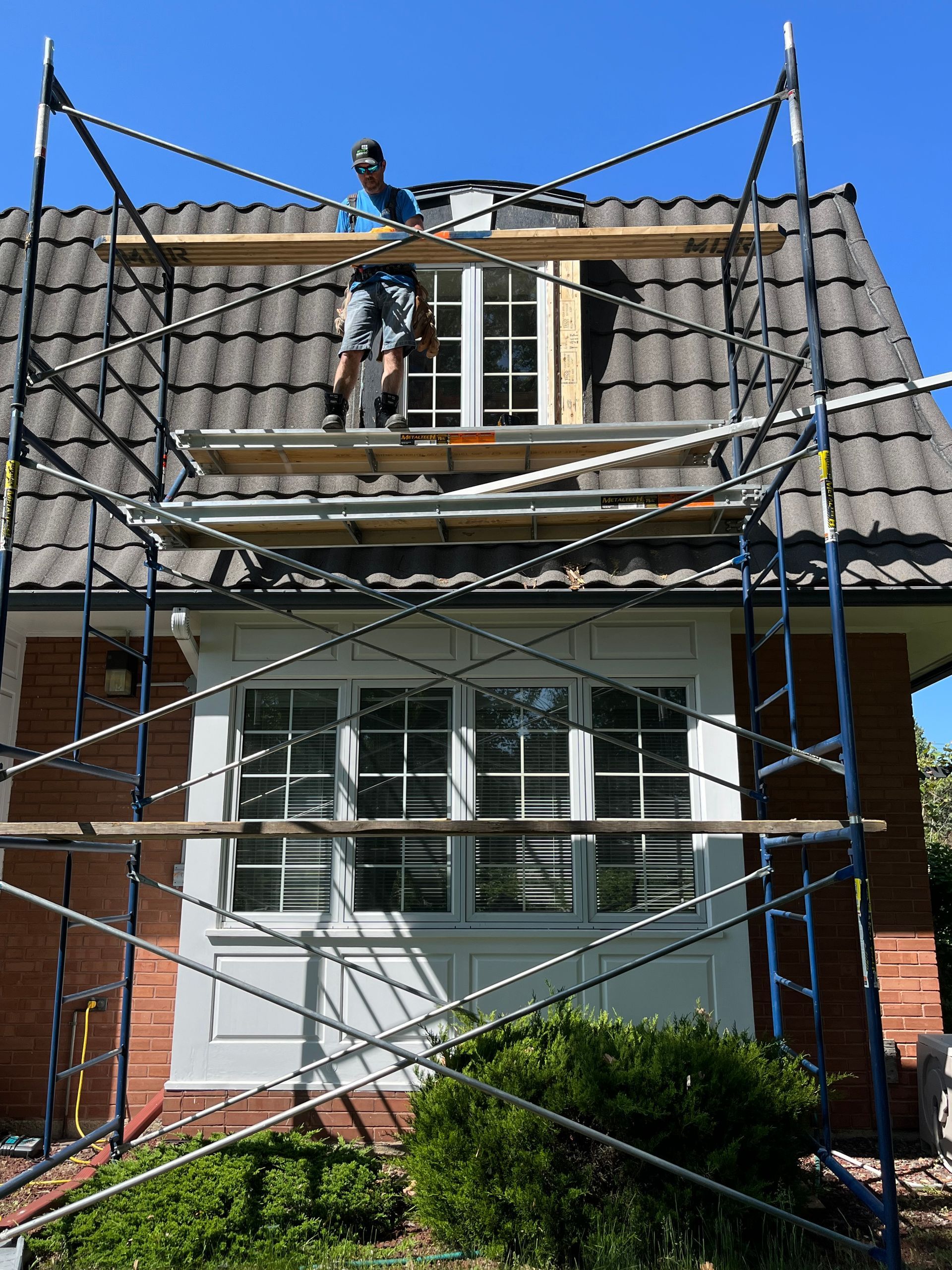Un homme est debout sur un échafaudage sur le toit d'une maison.