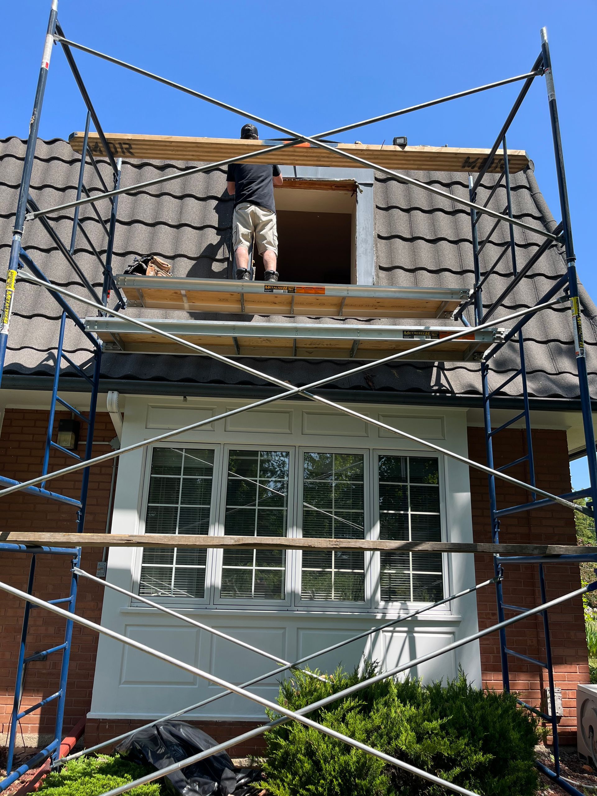 Un homme travaille sur le toit d'une maison sur un échafaudage.