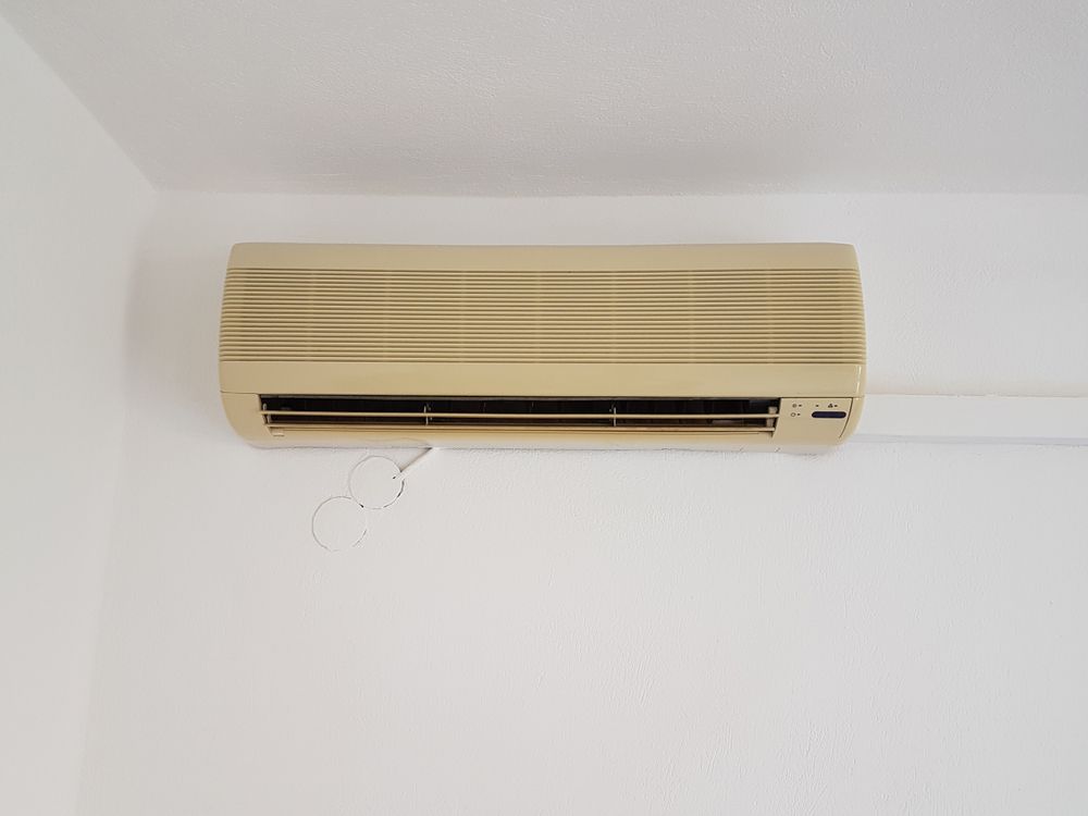 Tan Air Conditioning Unit Mounted on a White Wall — Brian Williams Electrical Air Solar in Noosa, QLD